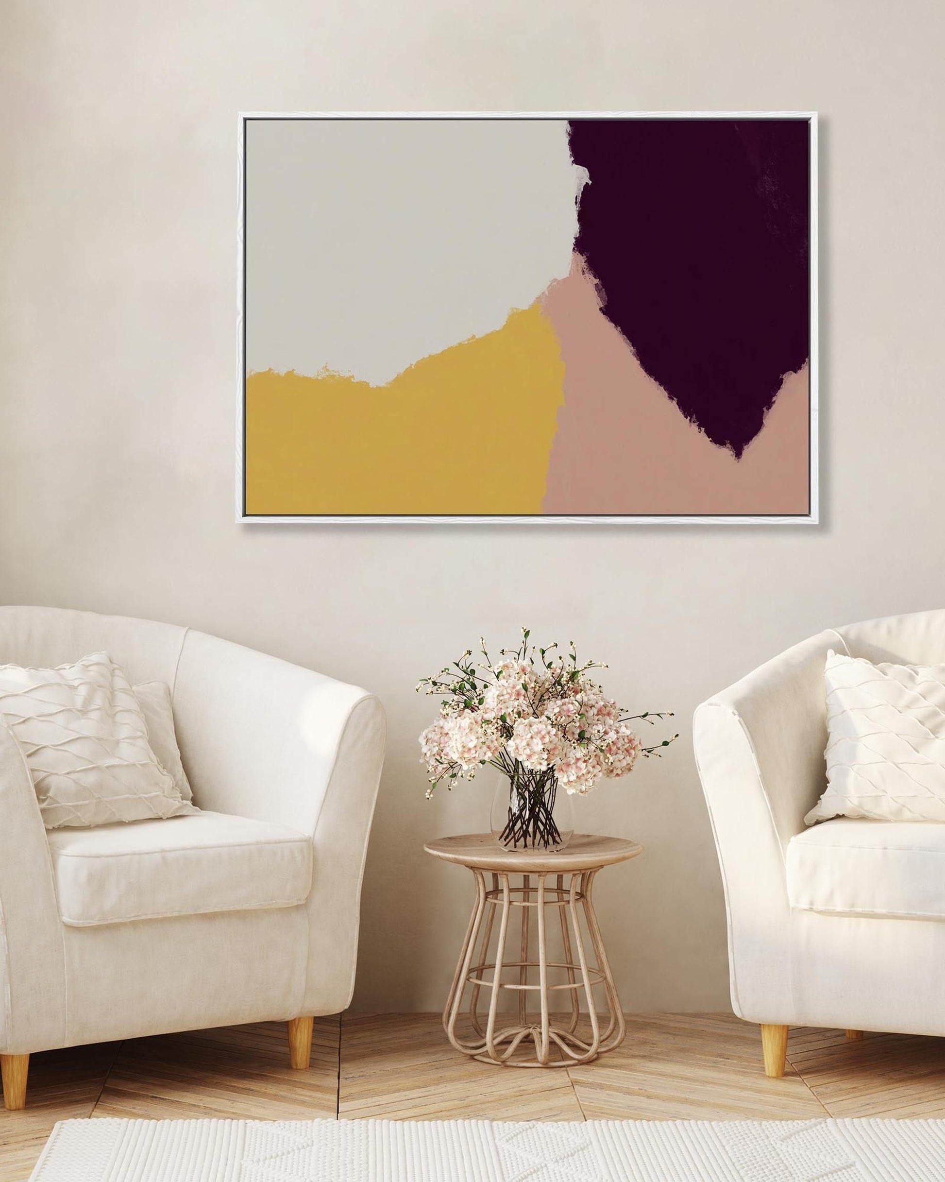 Abstract art piece on a wall above a small table with flowers, flanked by two white chairs.