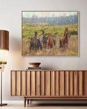 Framed artwork of horses in a field above a wooden cabinet.