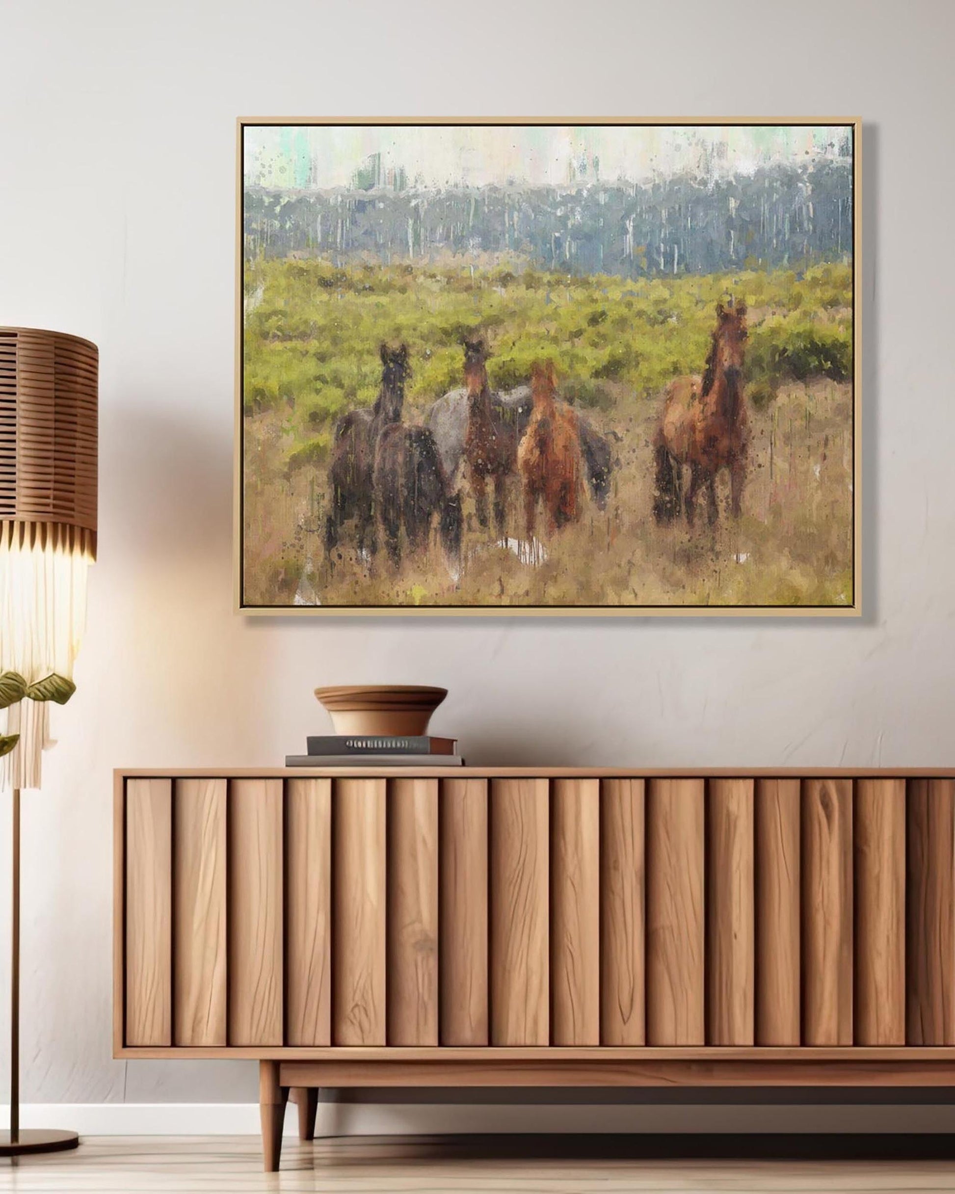 Framed artwork of horses in a field above a wooden cabinet.