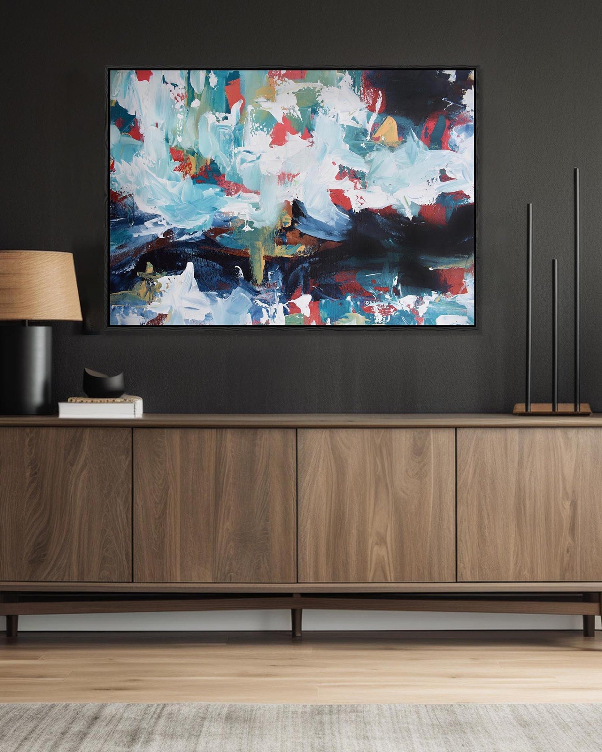 Abstract painting on a dark wall above a wooden cabinet