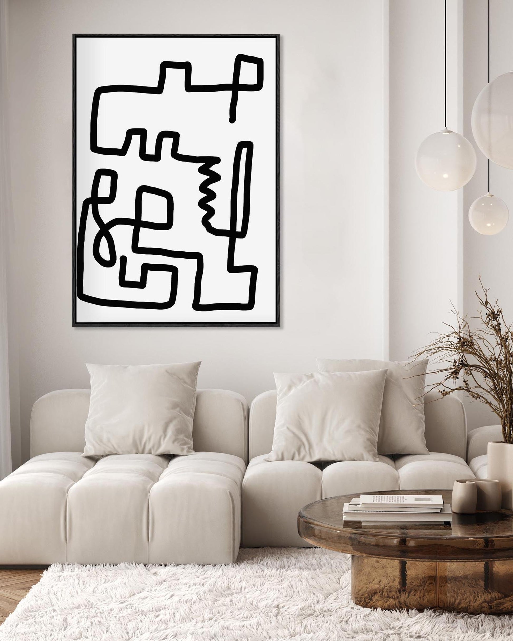 Abstract black and white artwork on a wall above a beige sofa in a living room.