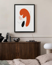 Abstract art piece on a wall above a wooden cabinet in a bedroom.