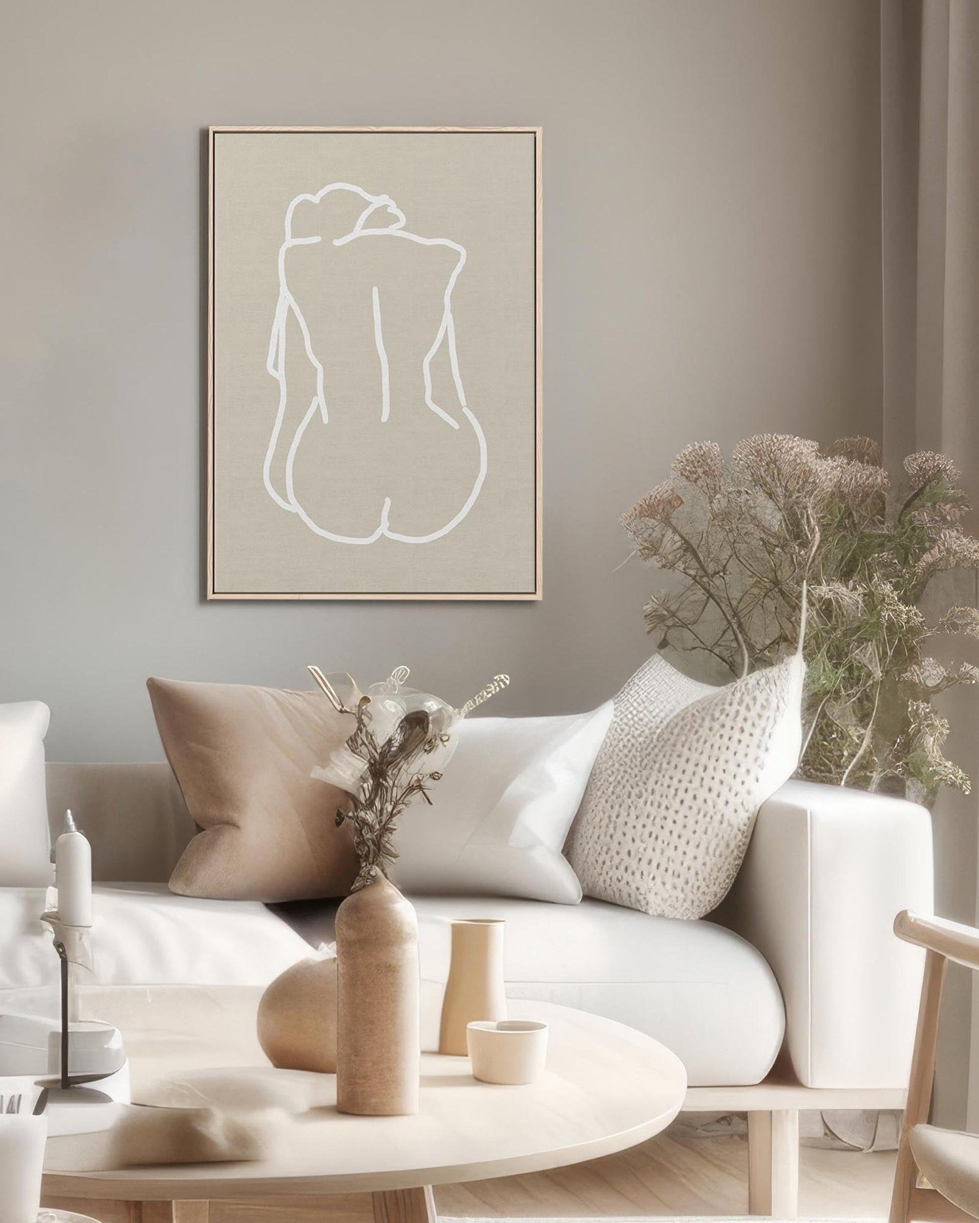 Modern living room with a white sofa, decorative pillows, and a framed abstract art piece on the wall.