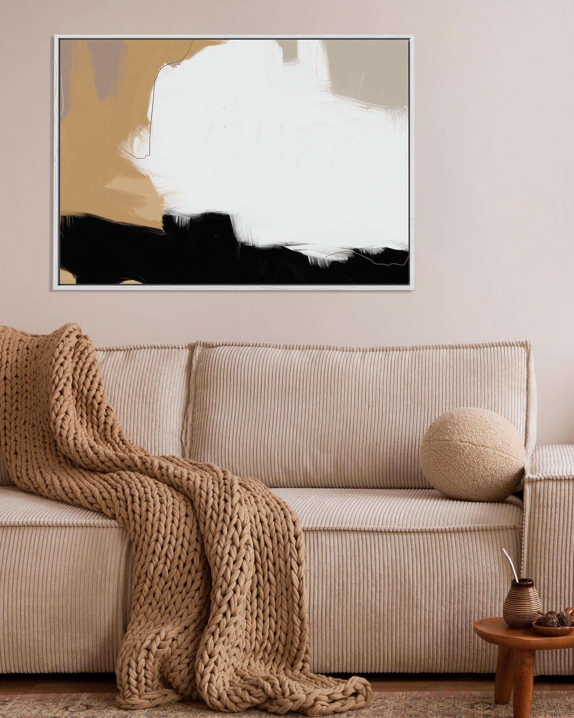 Living room with a beige sofa, abstract art on the wall, and a small wooden table.