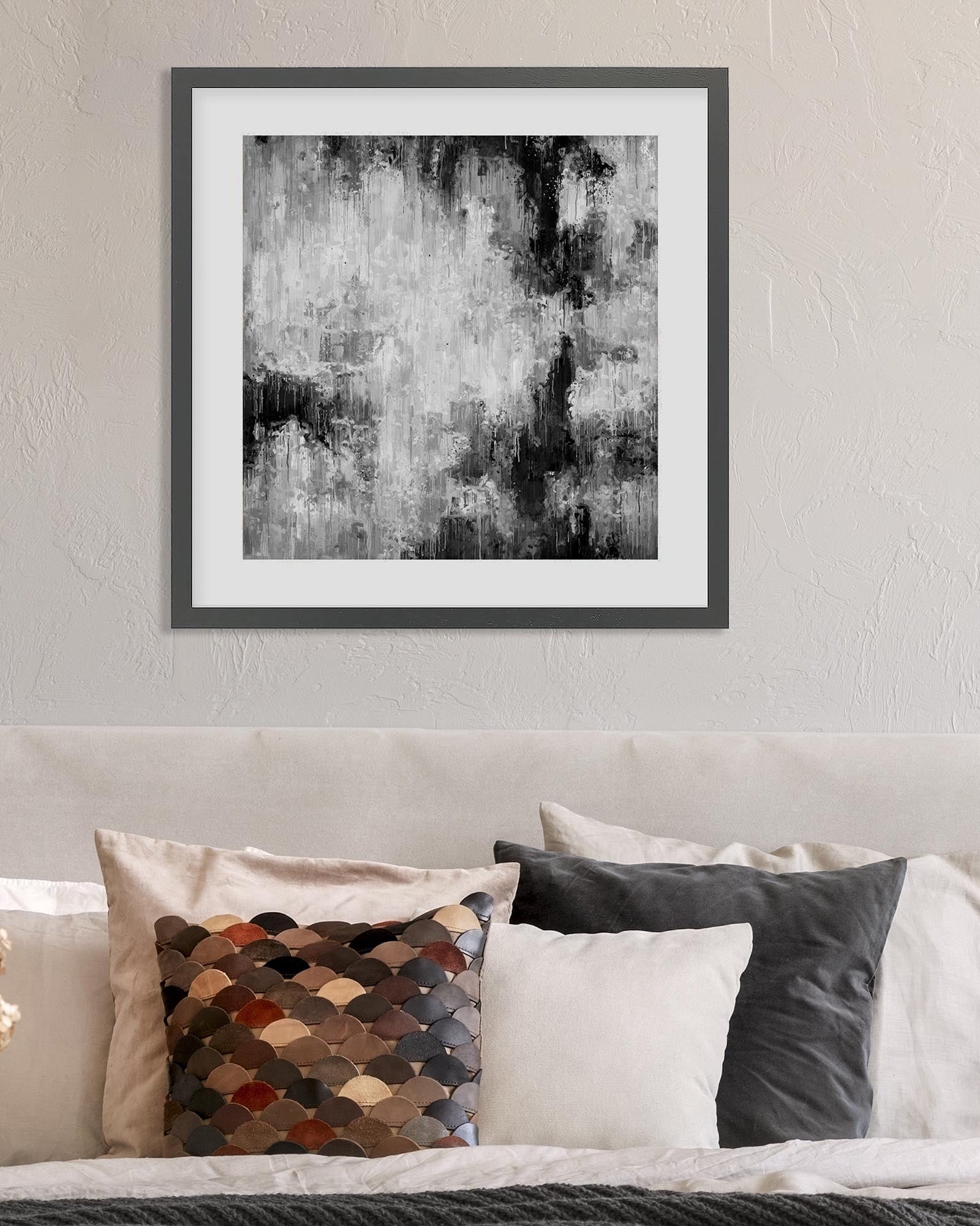 Framed abstract art piece on a wall above a sofa with decorative pillows.