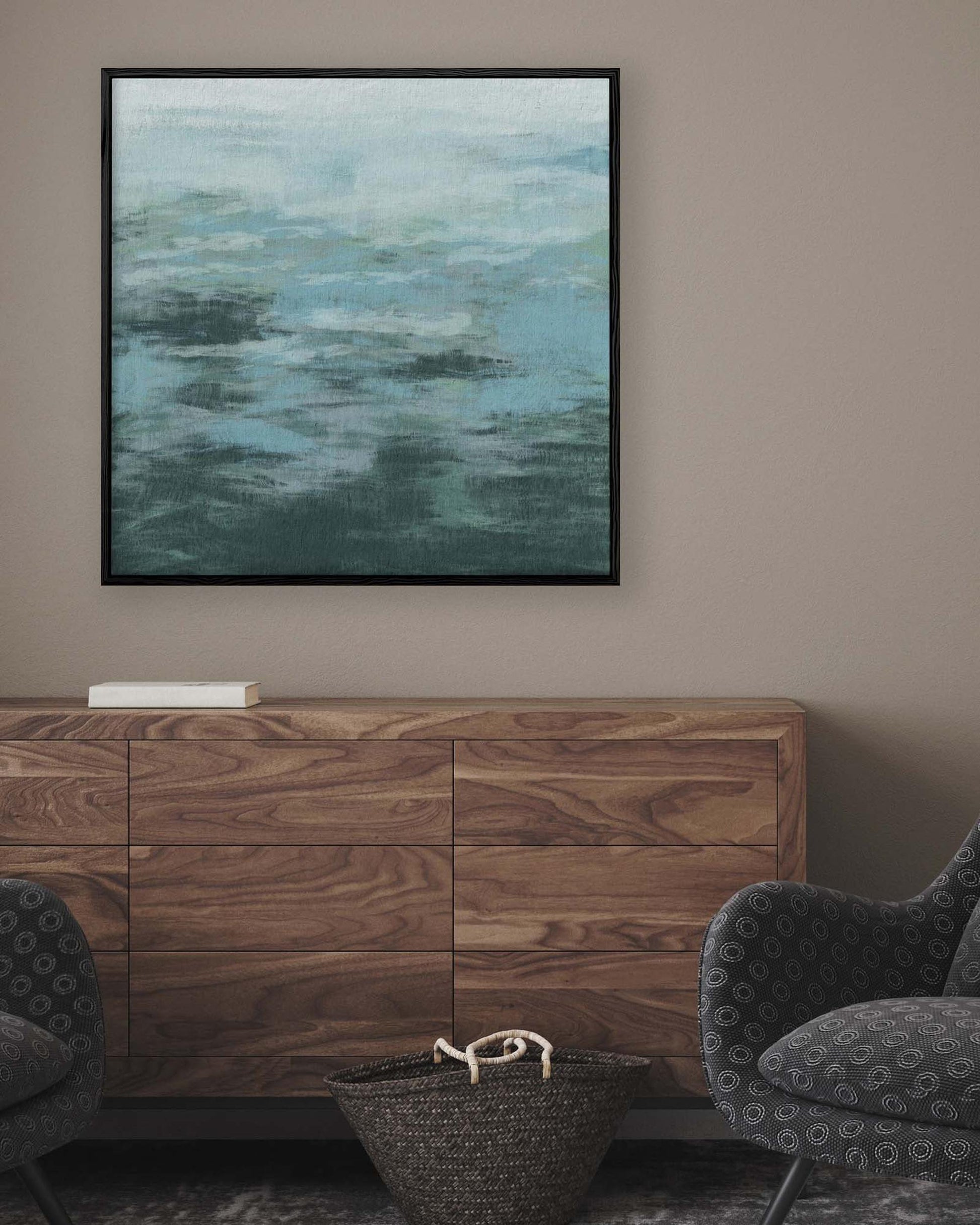 Abstract painting on a wall above a wooden cabinet with two armchairs.