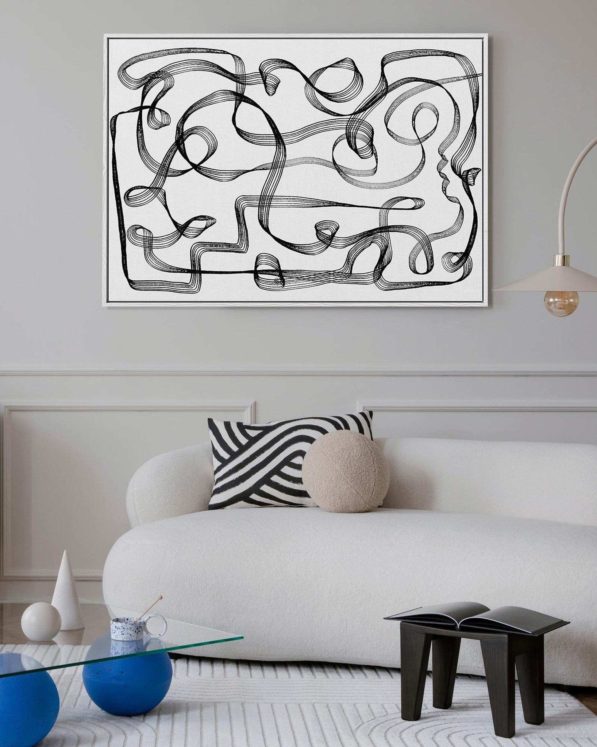 Modern living room with abstract artwork on the wall, white sofa, and decorative items.