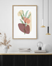 Framed abstract art print with leaves on a wall above a wooden shelf.