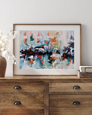 Framed abstract painting on a wooden dresser with decorative items.