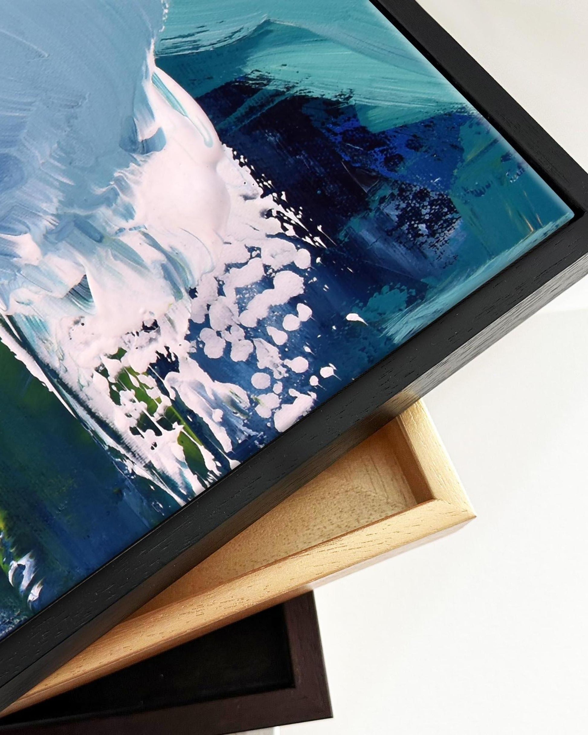 Framed abstract painting with blue and white brushstrokes on a light background