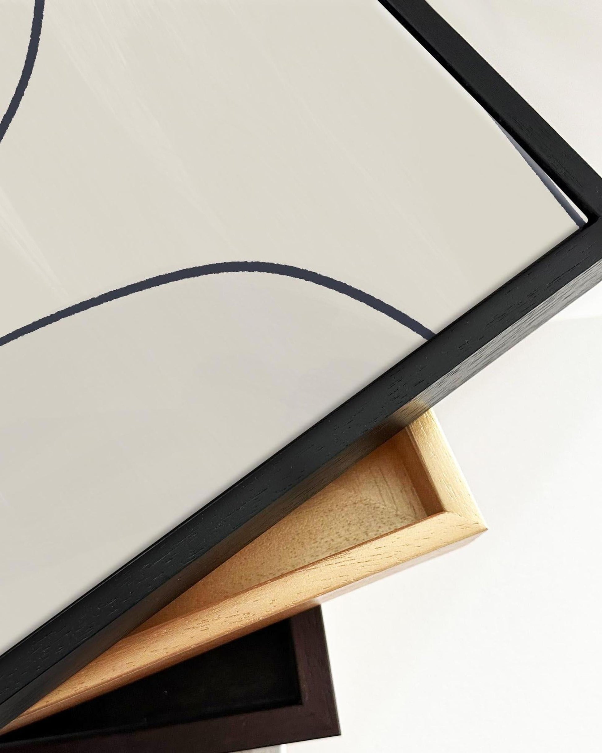 Close-up of a framed picture with a black frame and wooden backer.