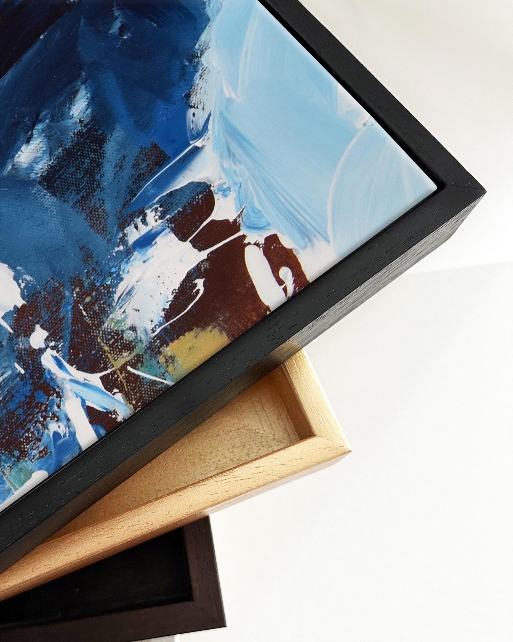Abstract painting with blue, white, and brown colors in a black frame on a white background