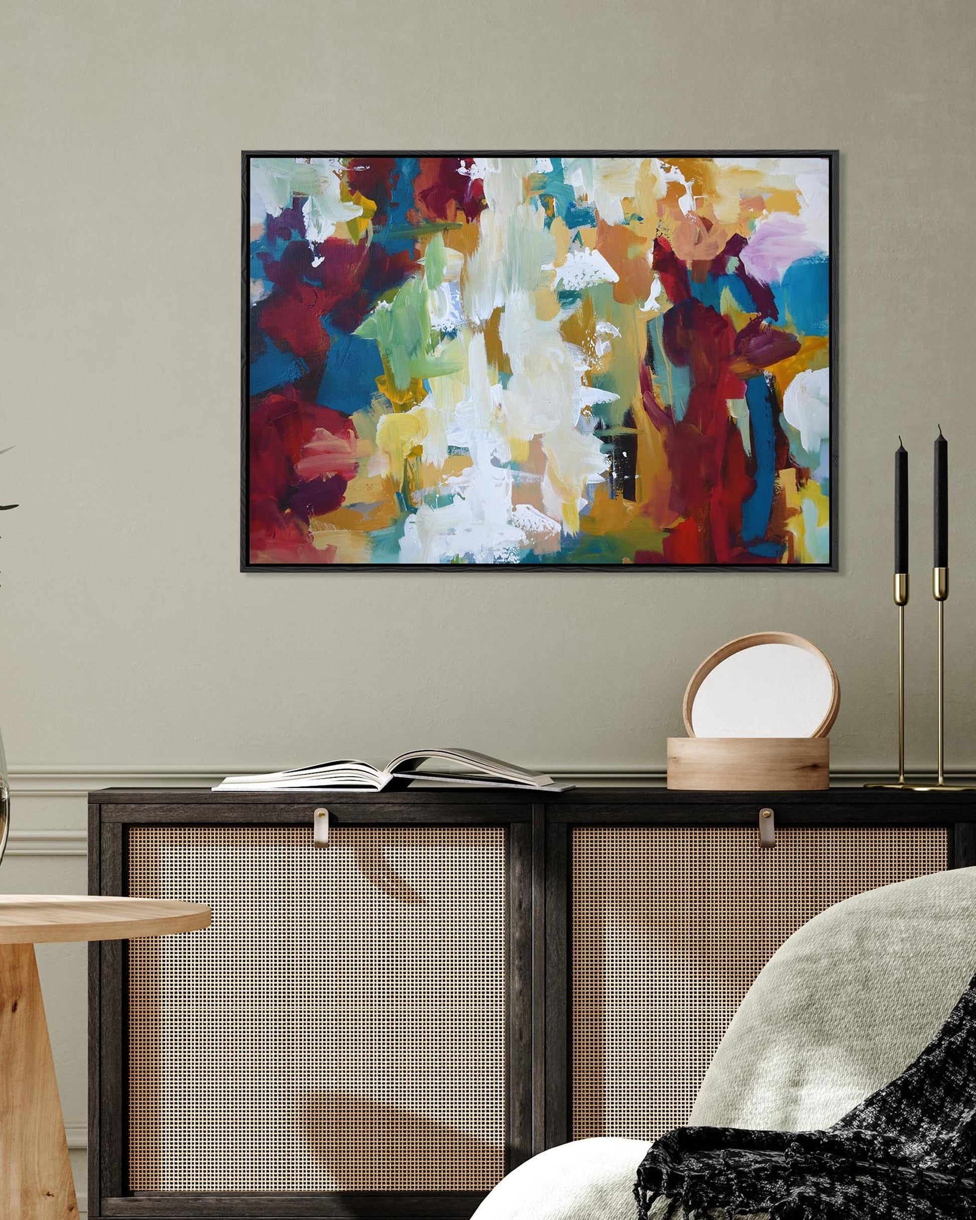 Colorful abstract painting on a wall above a wooden side table and chair.