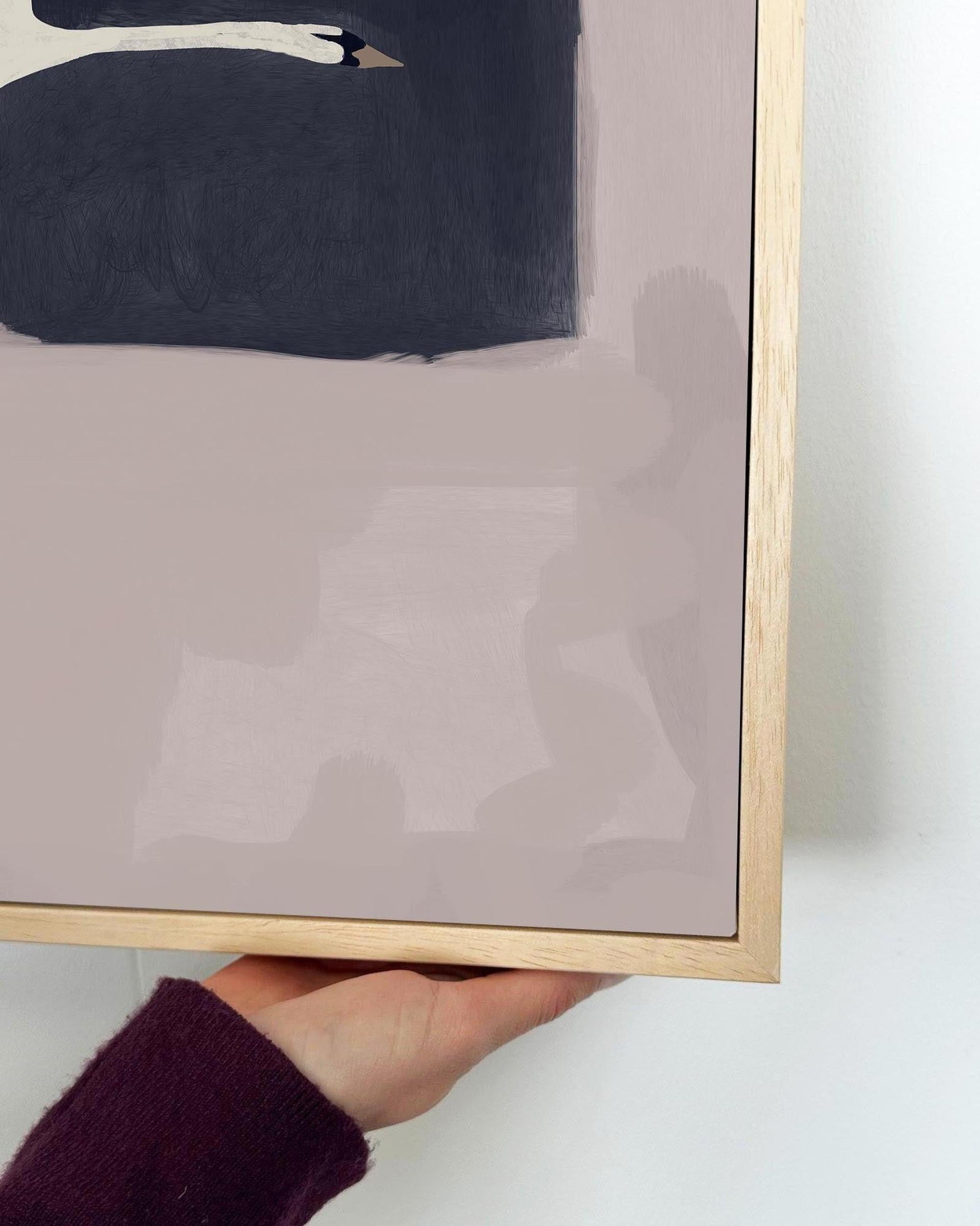 Framed abstract art with a gold frame held by a hand on a white background