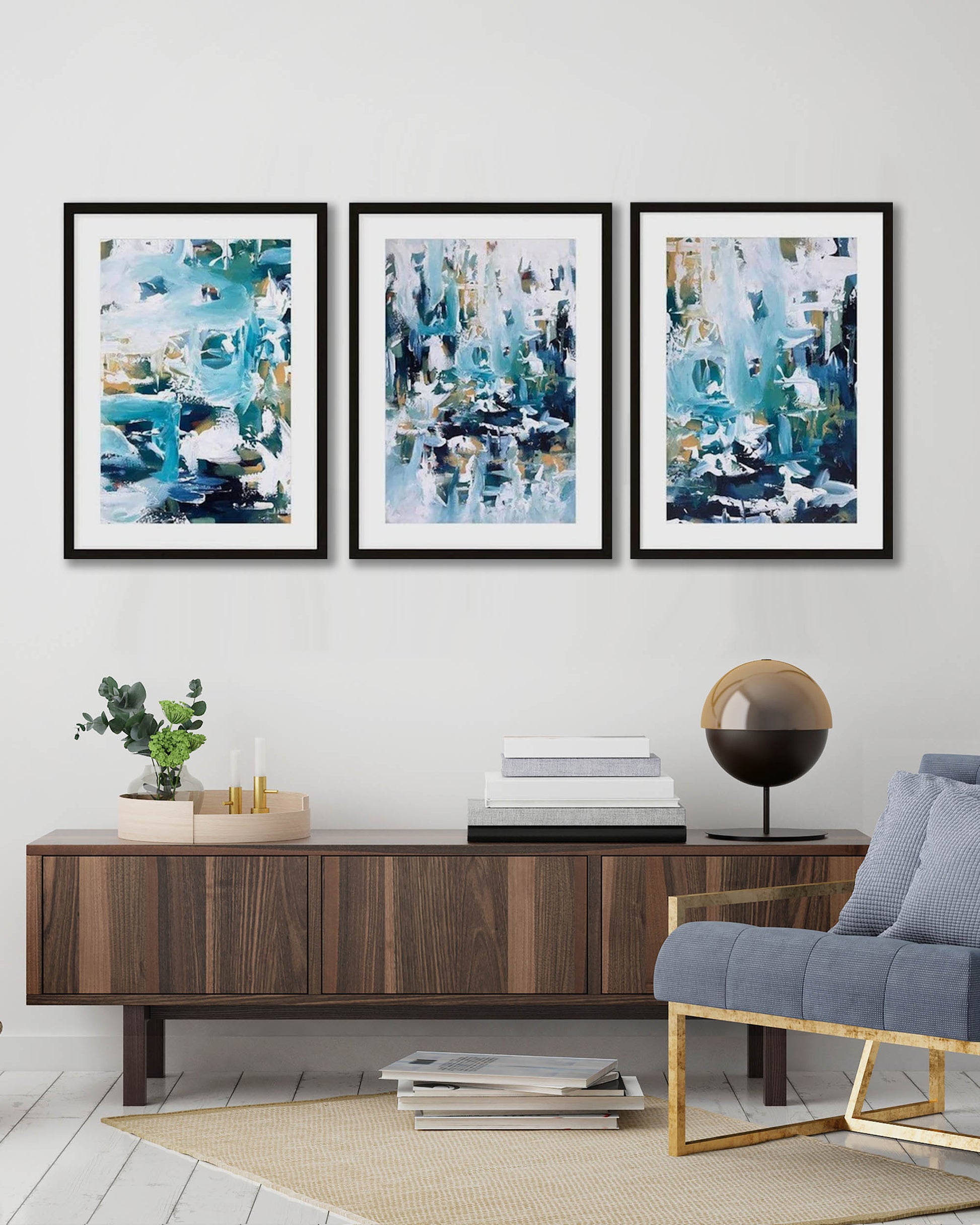 large modern coastal abstract blue wall art, modern framed pictures in contemporary living room with walnut sideboard, plants, candles, books and large modern sculpture and grey chair, brown natural hessian rug