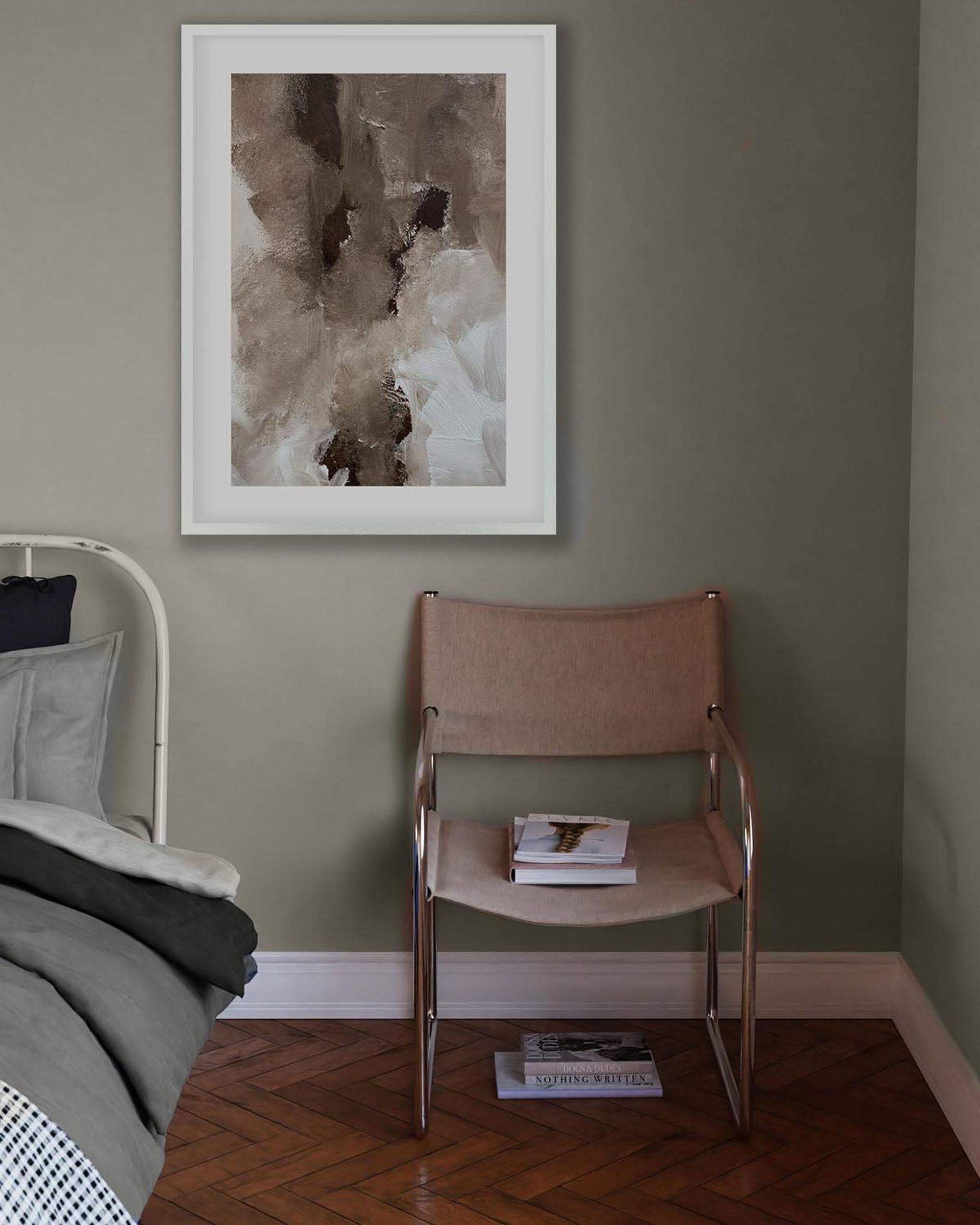 Room interior with a bed, chair, and framed abstract art on a wall.