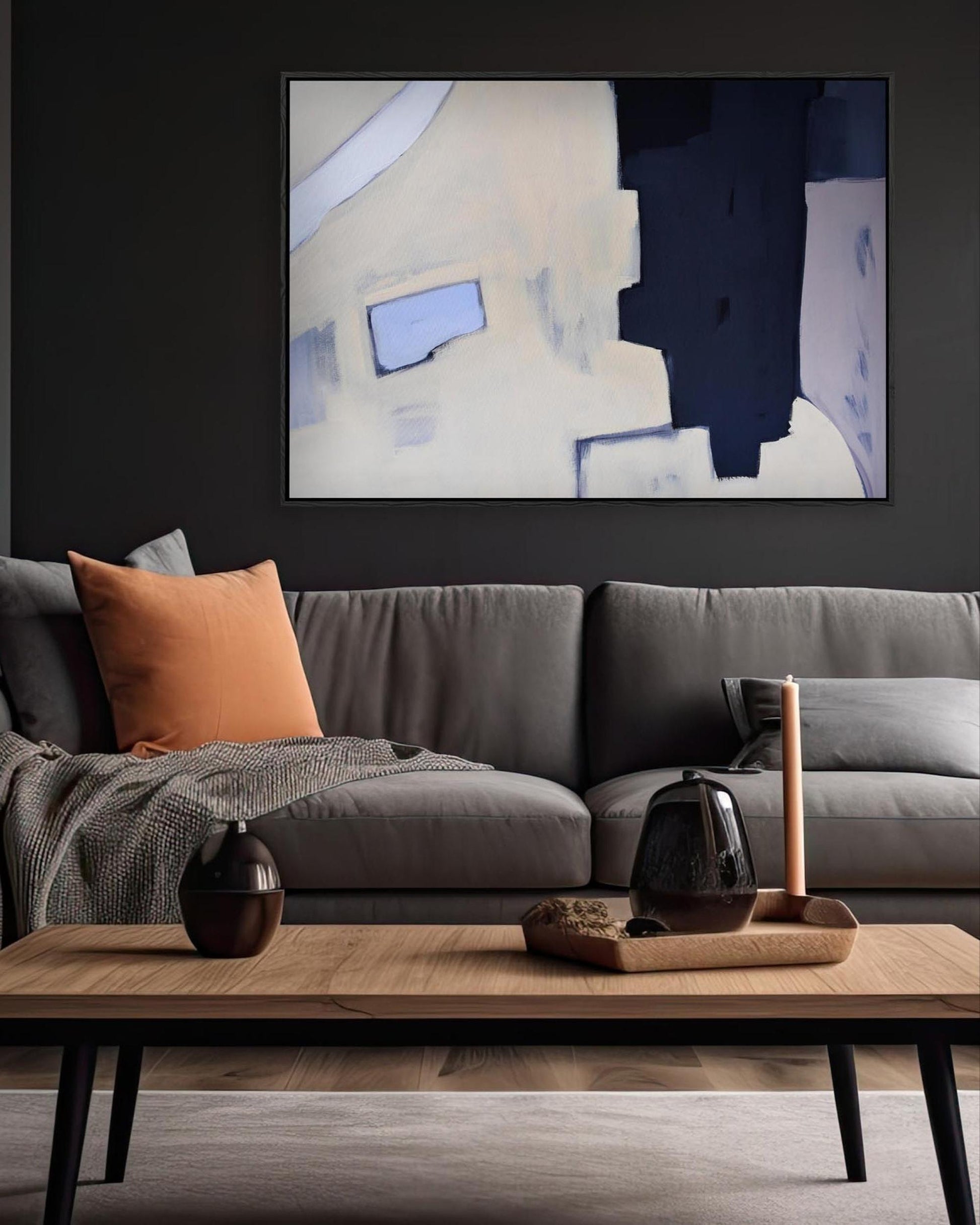 Modern living room with a gray sofa, wooden coffee table, and abstract art on the wall.