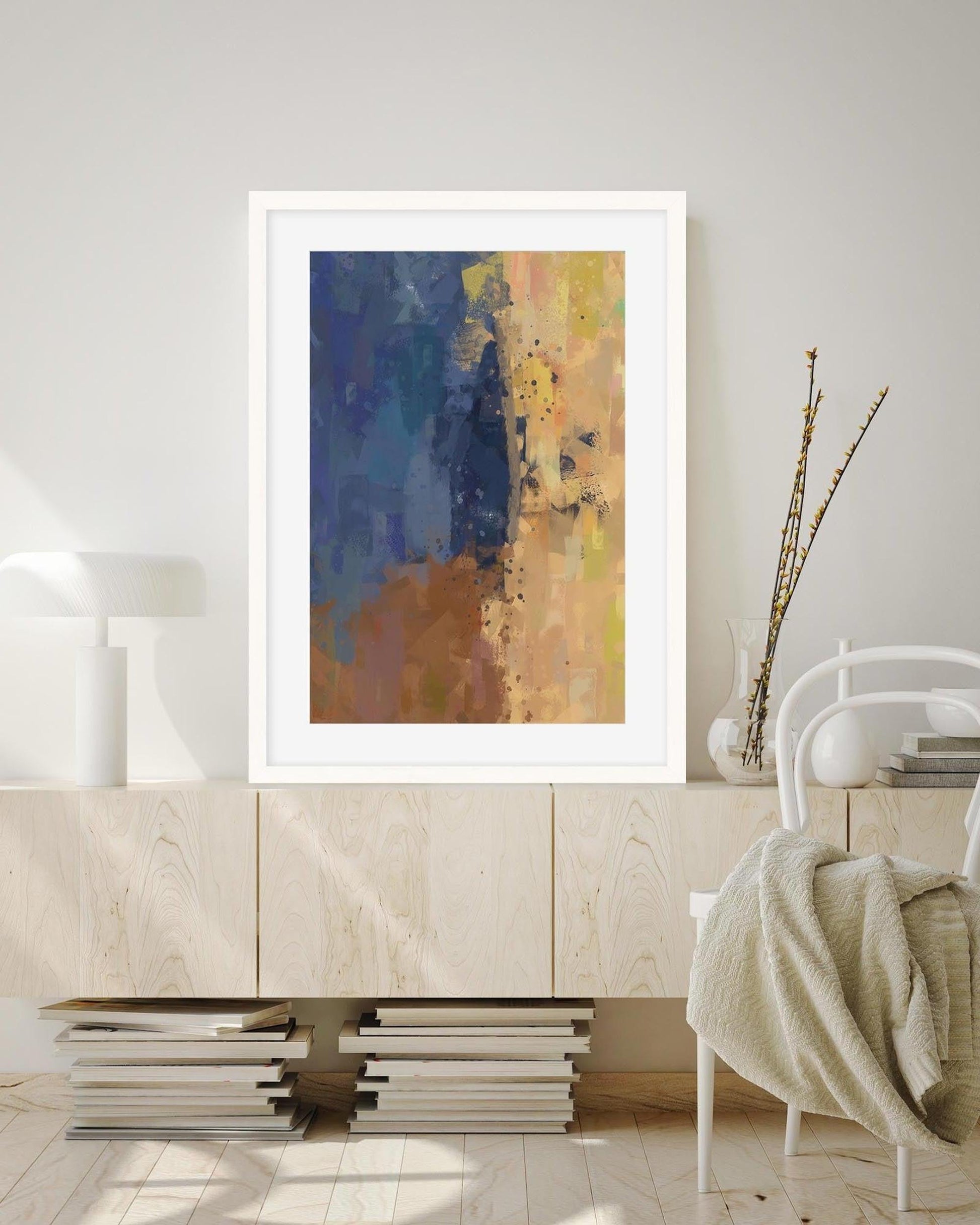 Abstract art print in a white frame on a wall above a wooden cabinet.
