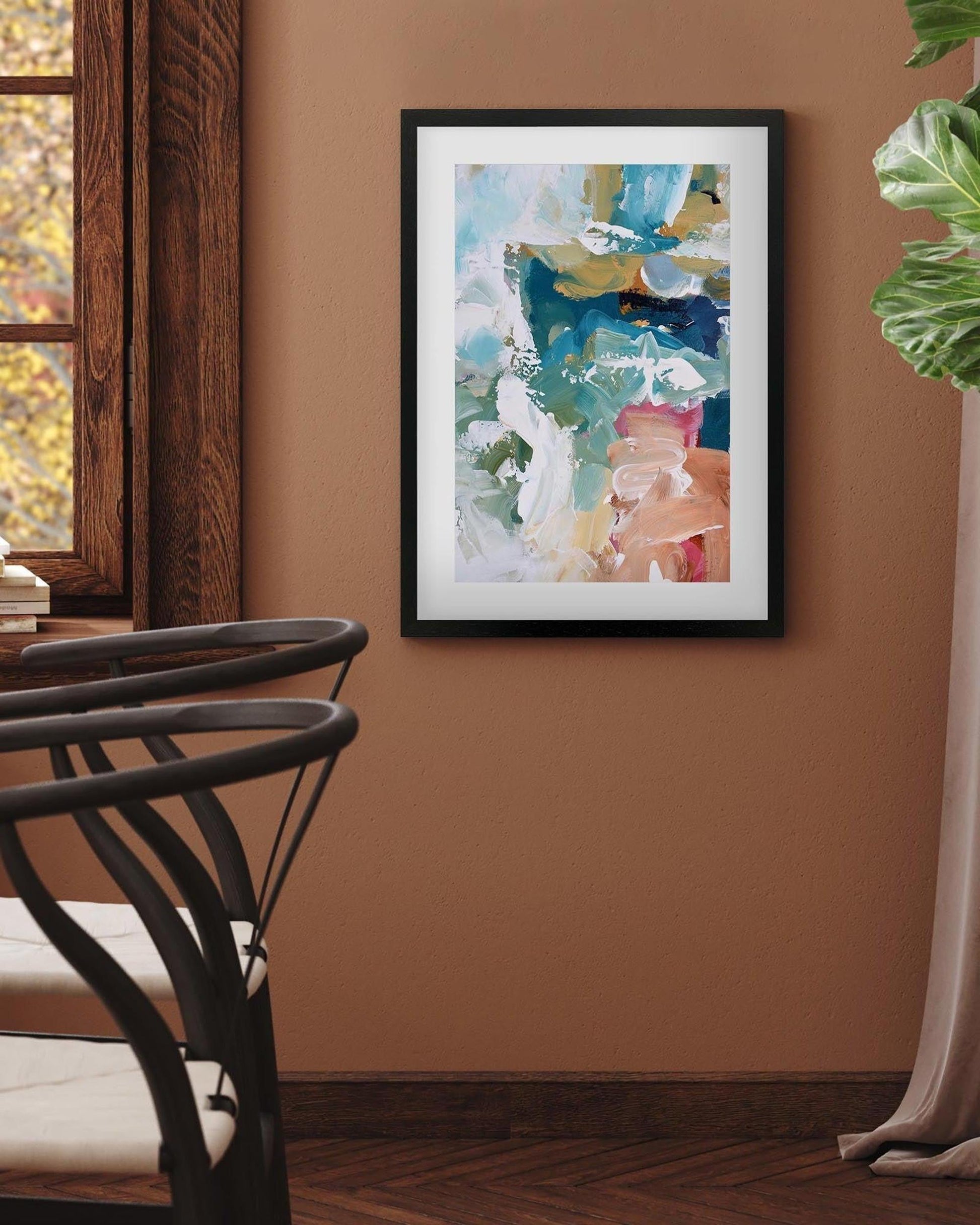 Abstract art print on a wall in a room with a chair and window.