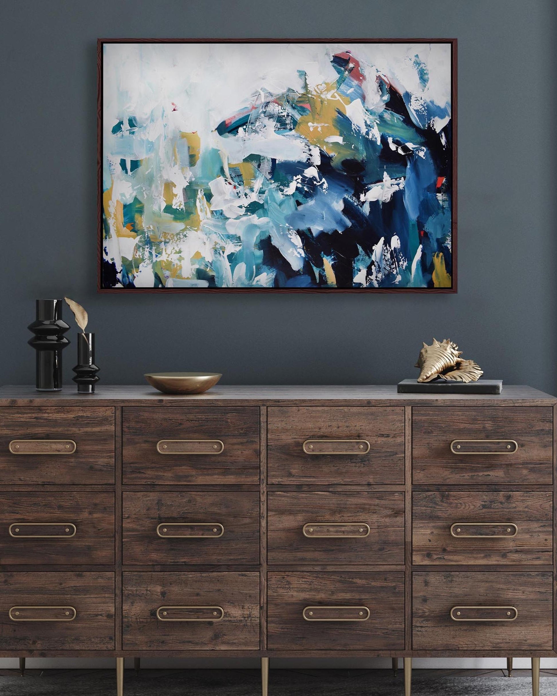 Wooden dresser with decorative items and abstract painting on a dark gray wall