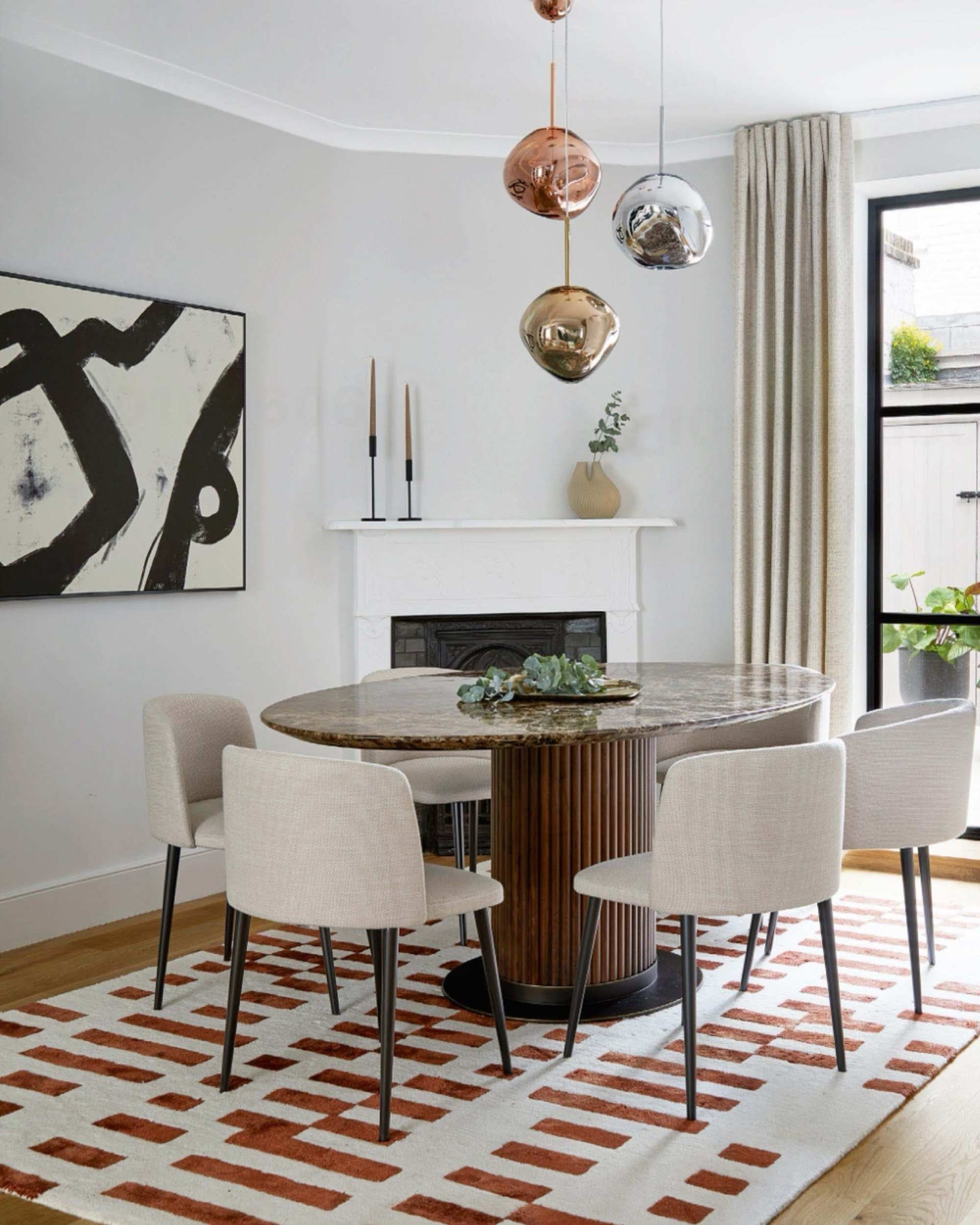 Dining room with a round wooden table and four chairs on a patterned rug.