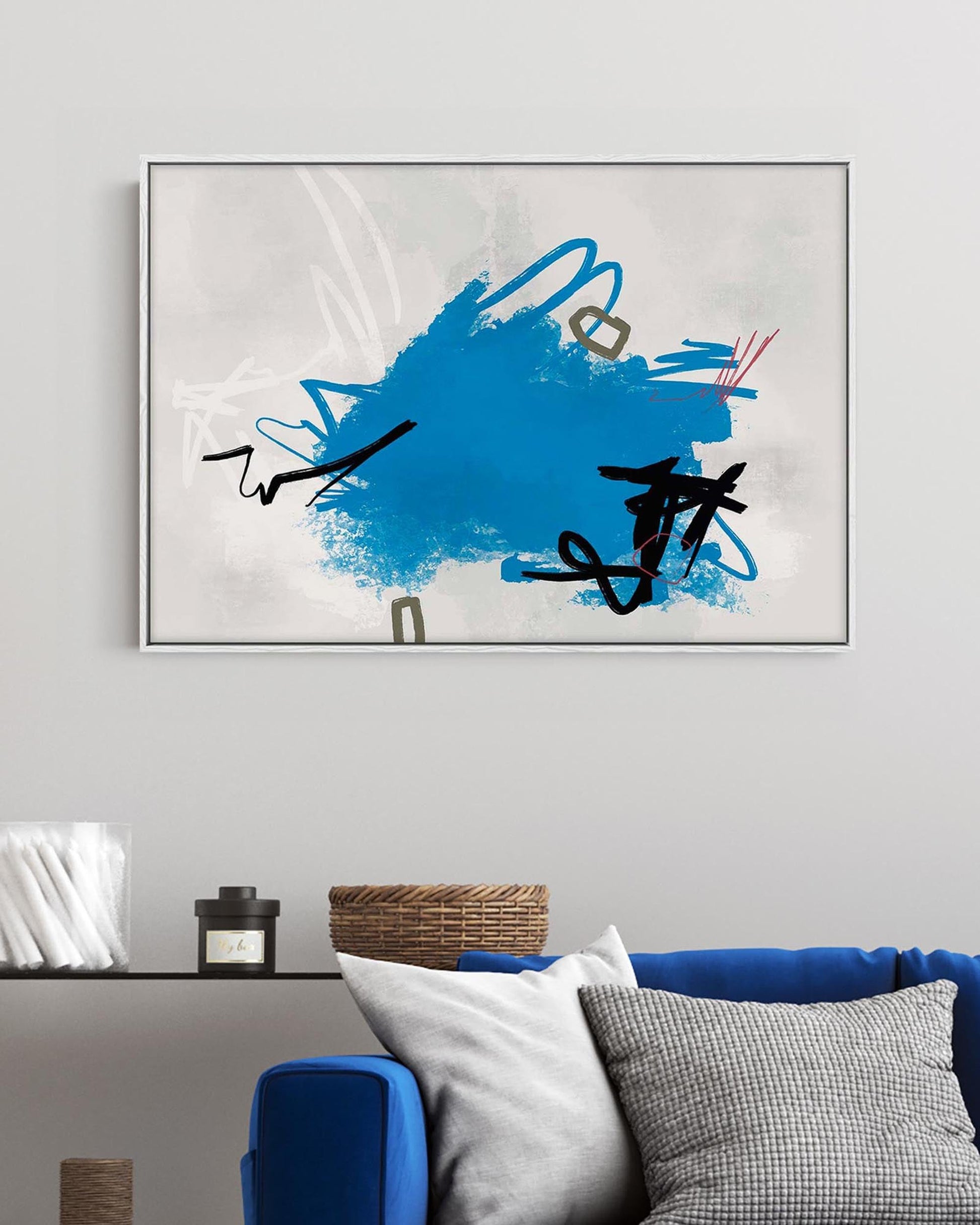Abstract art piece with blue and black design on a wall above a blue sofa.