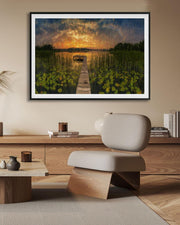 Framed artwork of a sunset over water with a dock, displayed in a modern living room.