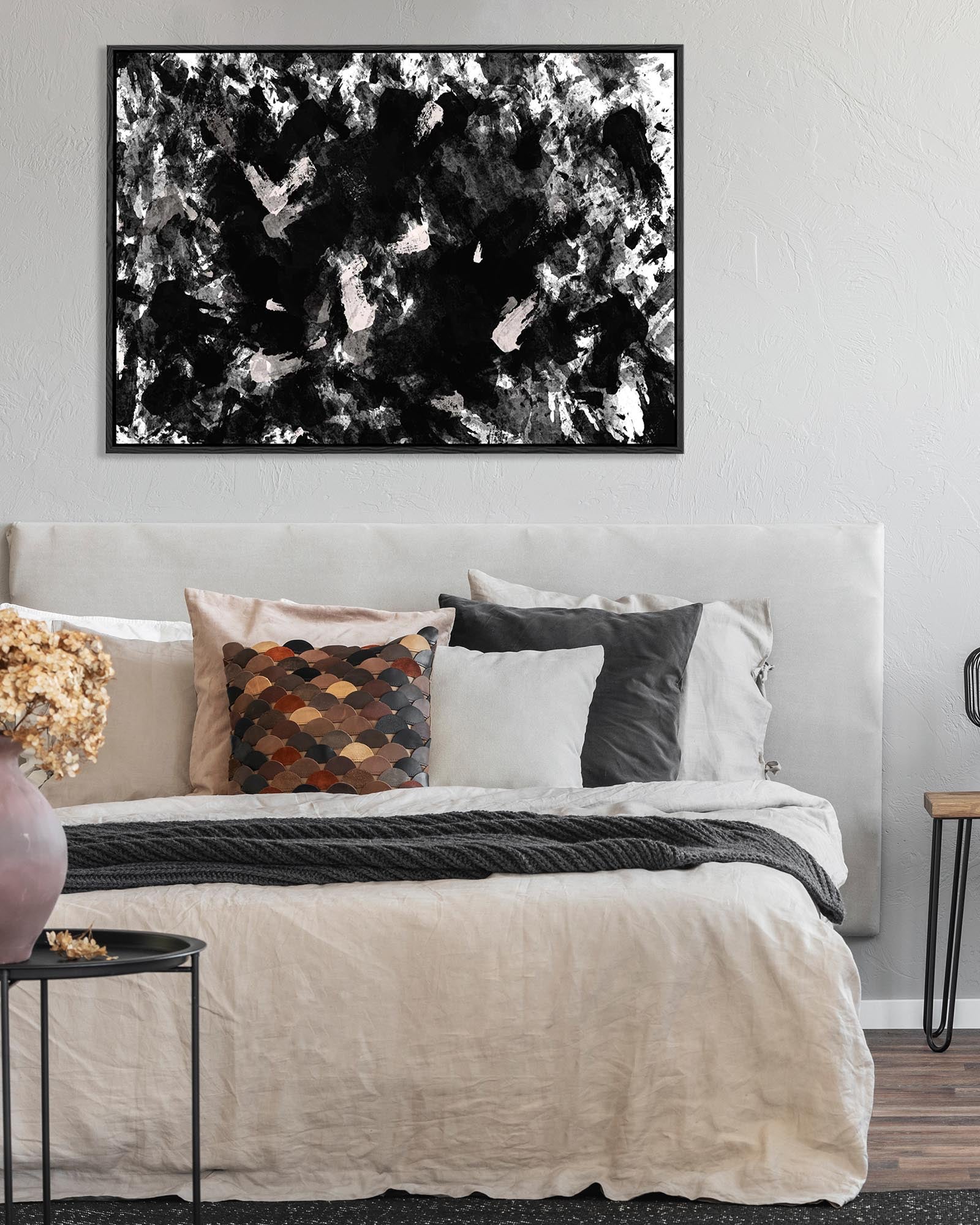 Abstract black and white painting above a bed with decorative pillows.