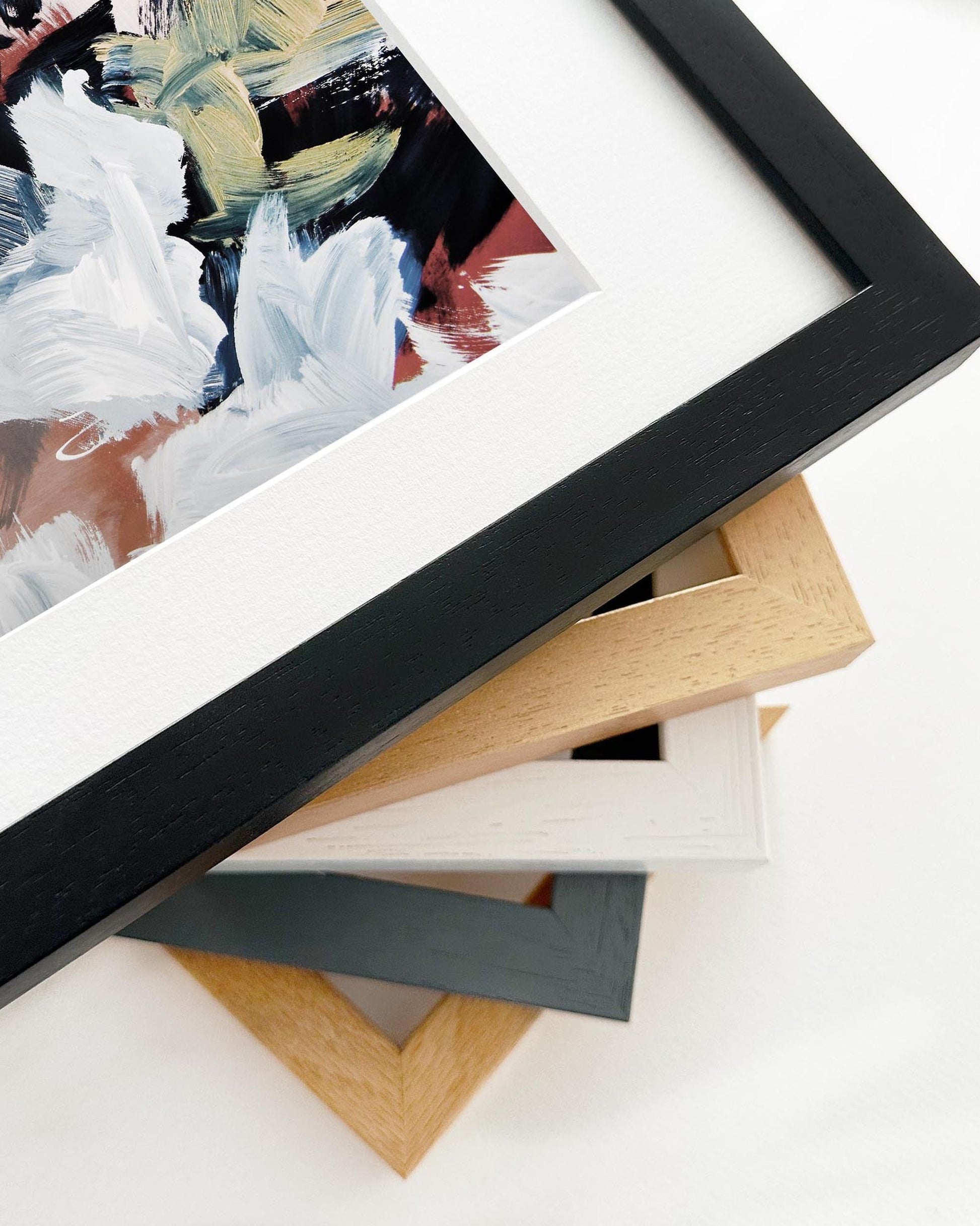 Collection of variously framed artworks on a white surface