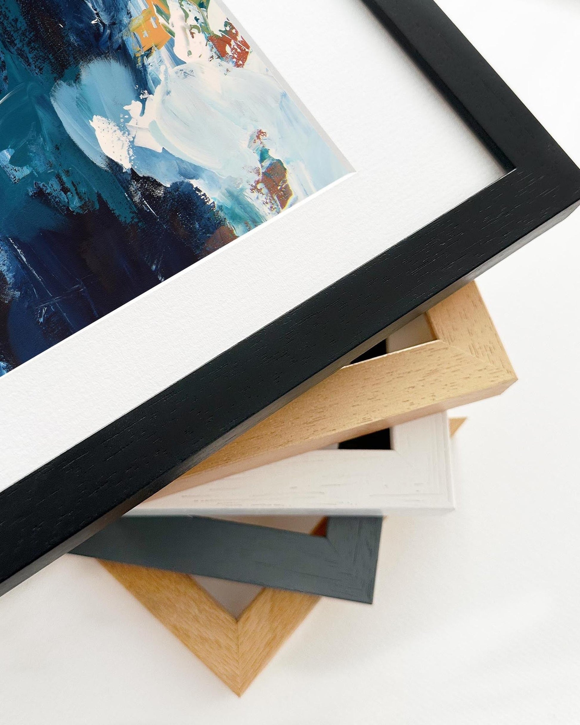 Framed abstract painting with a stack of variously colored frames on a white background