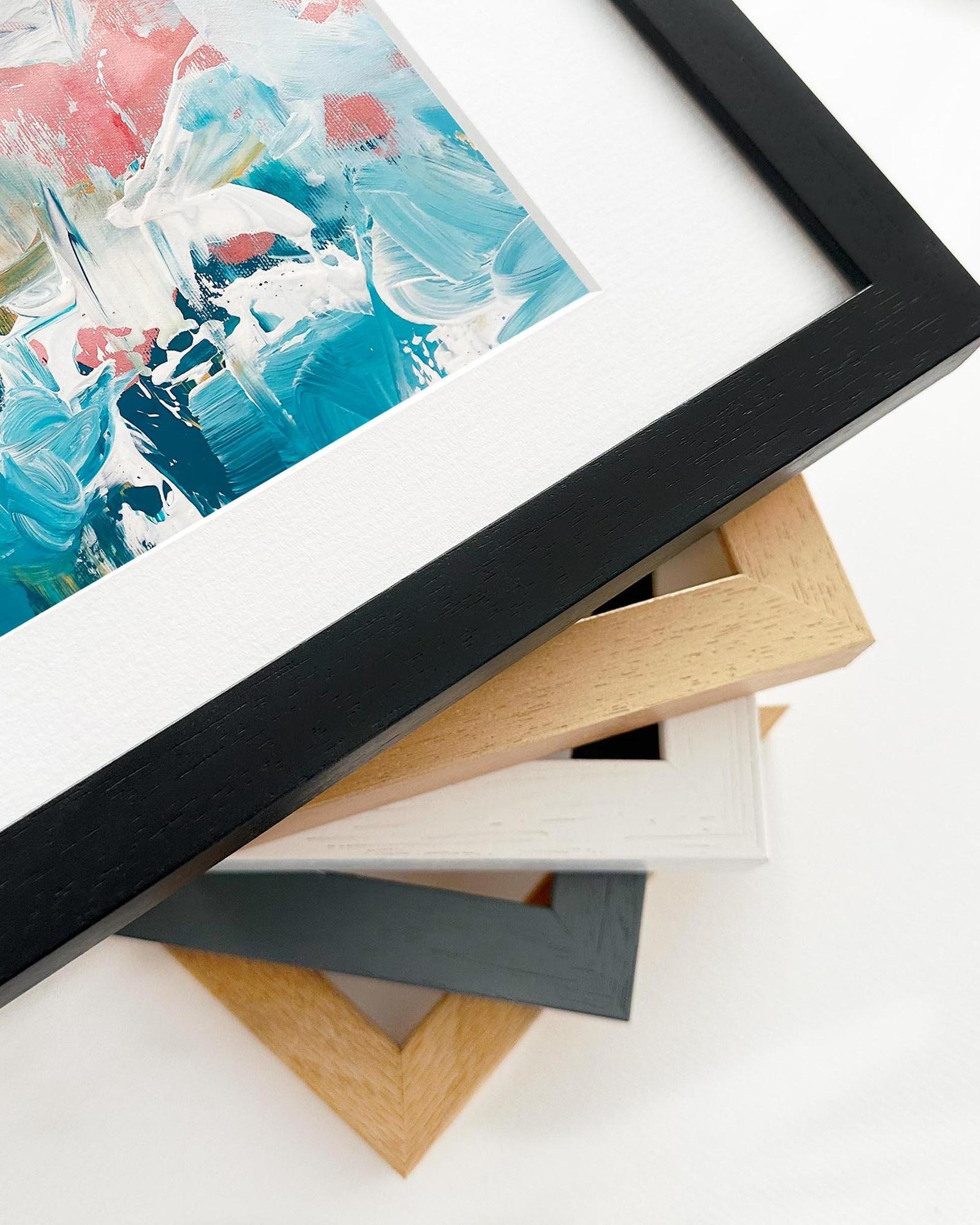 Close-up of a framed abstract painting with various color frames on a white surface