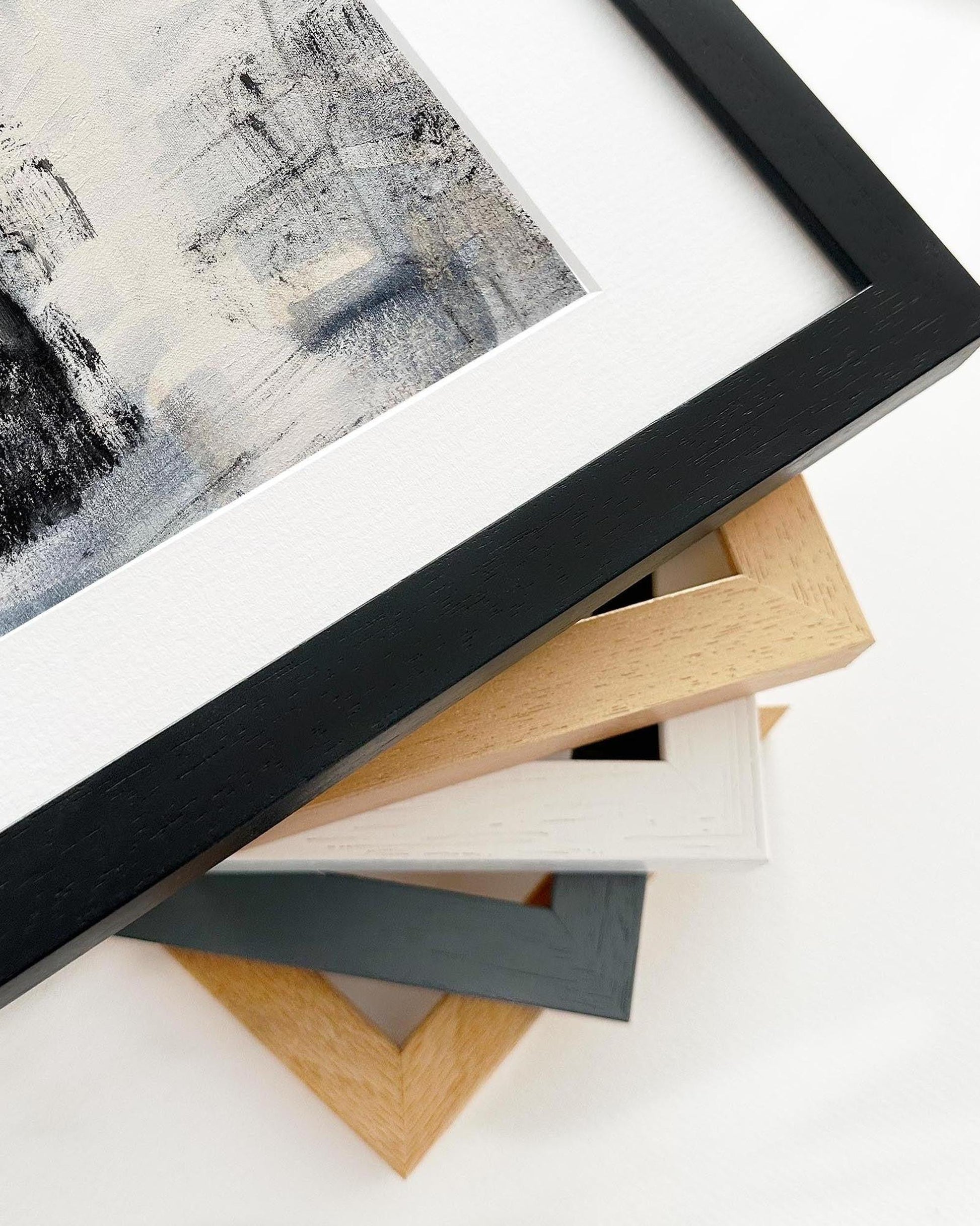 Collection of various picture frames on a white surface with abstract art in the background.