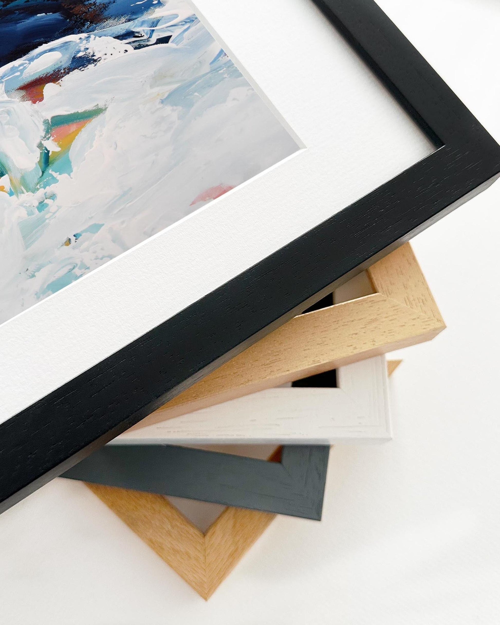 Stack of picture frames in various colors on a white surface