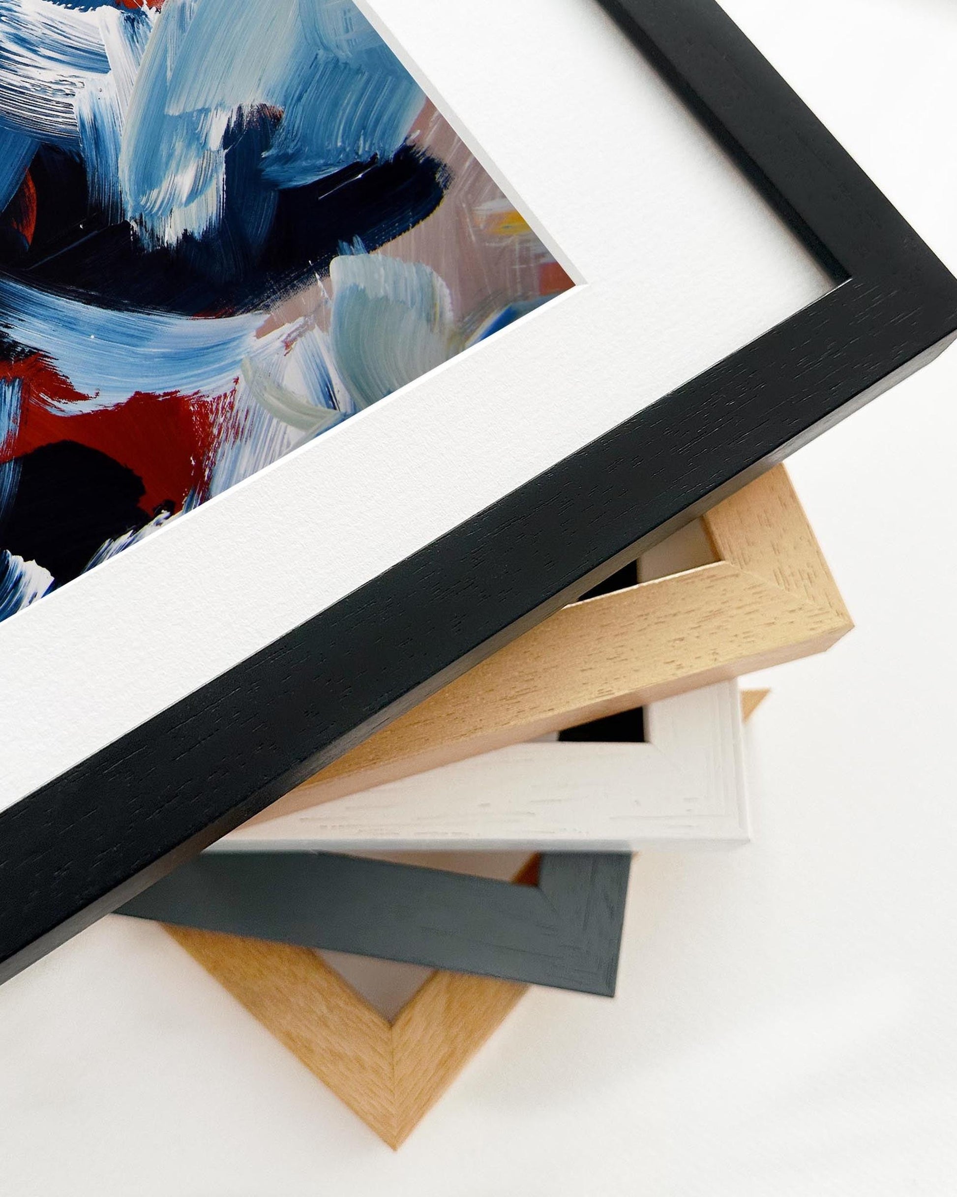 Collection of various picture frames on a white surface with a painting in the background.