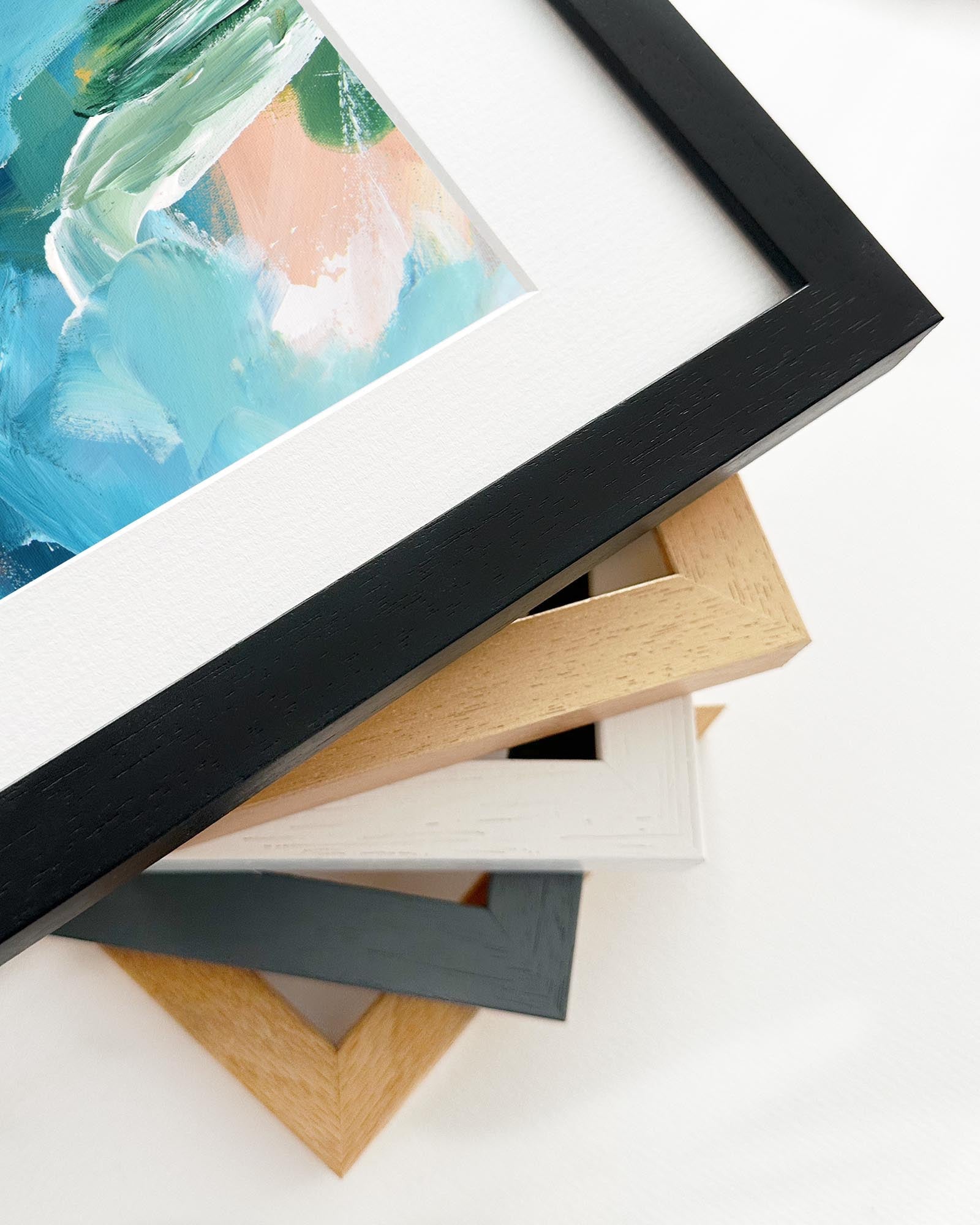 Stack of variously framed artworks on a white background