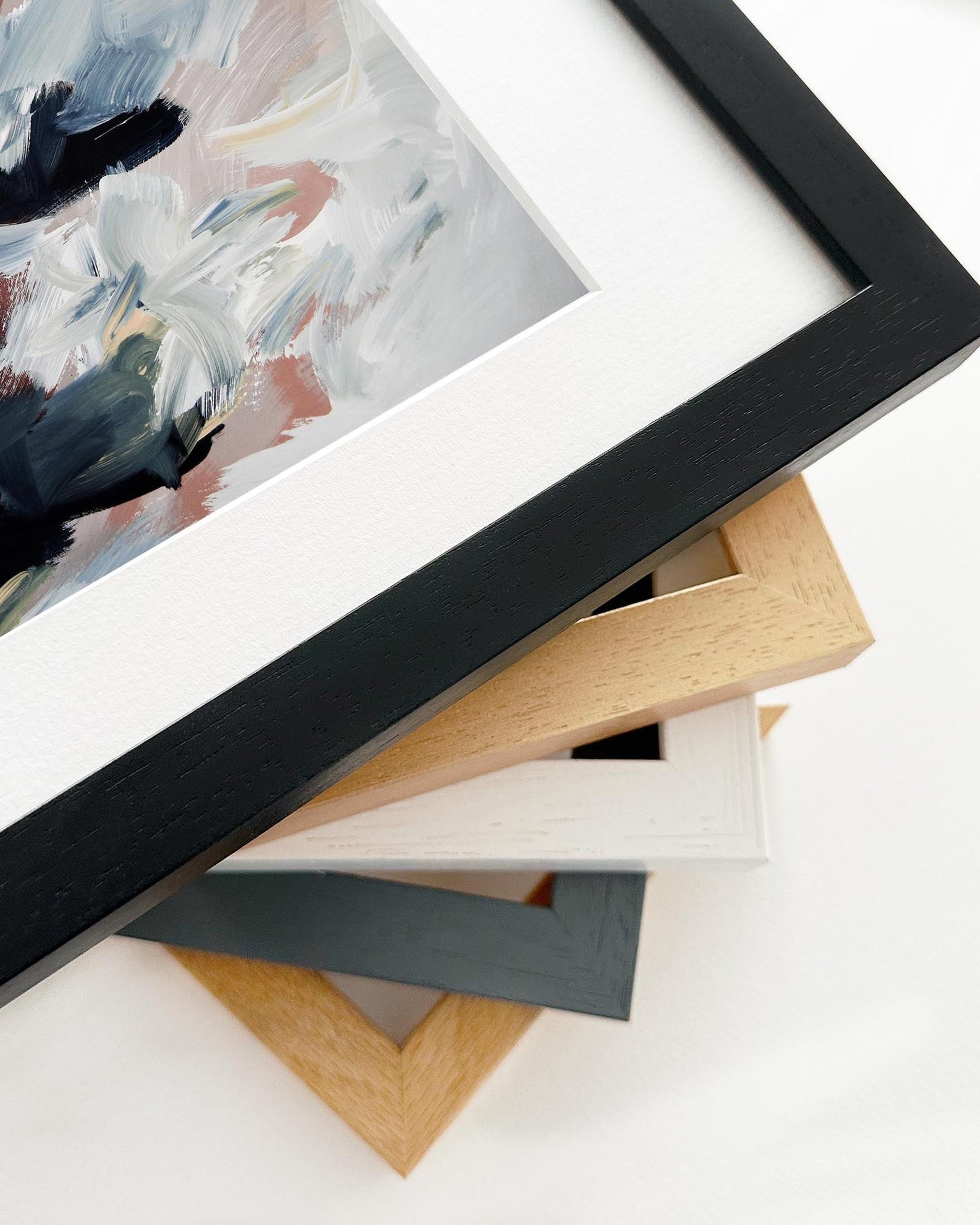 Close-up of various picture frames with a painting in the background