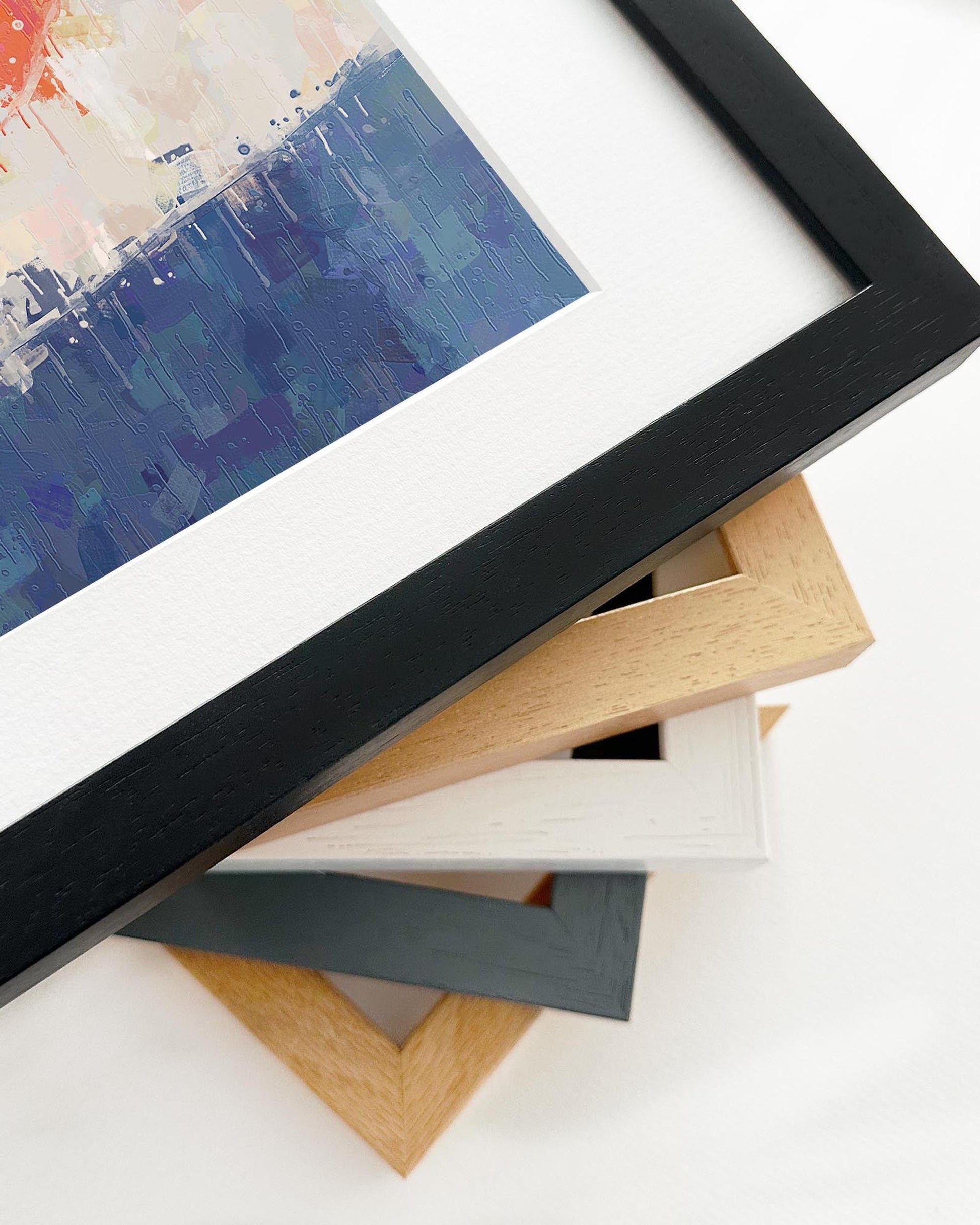 Close-up of various picture frames with a colorful painting in the background