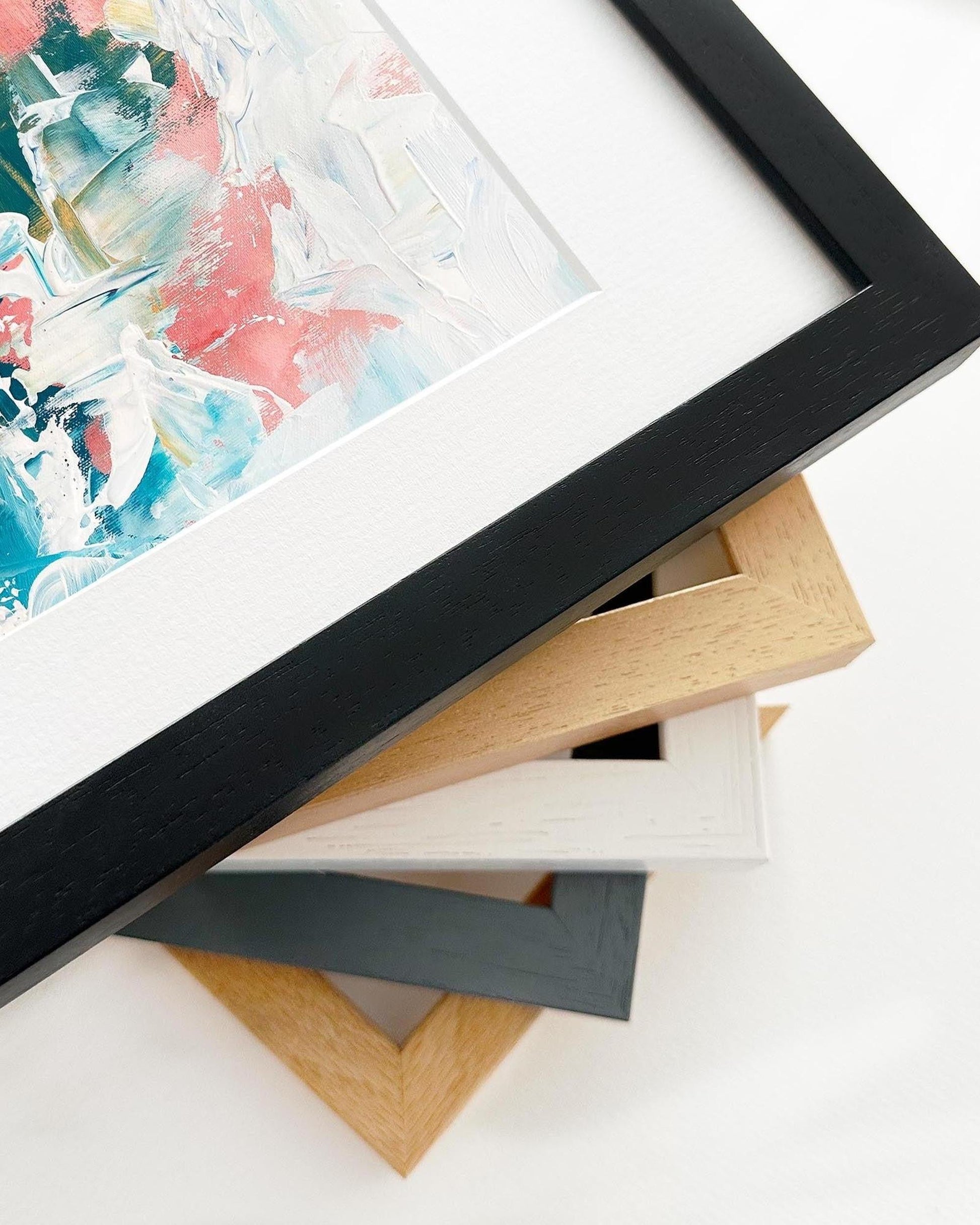 Close-up of a stack of picture frames with a partially visible abstract painting.