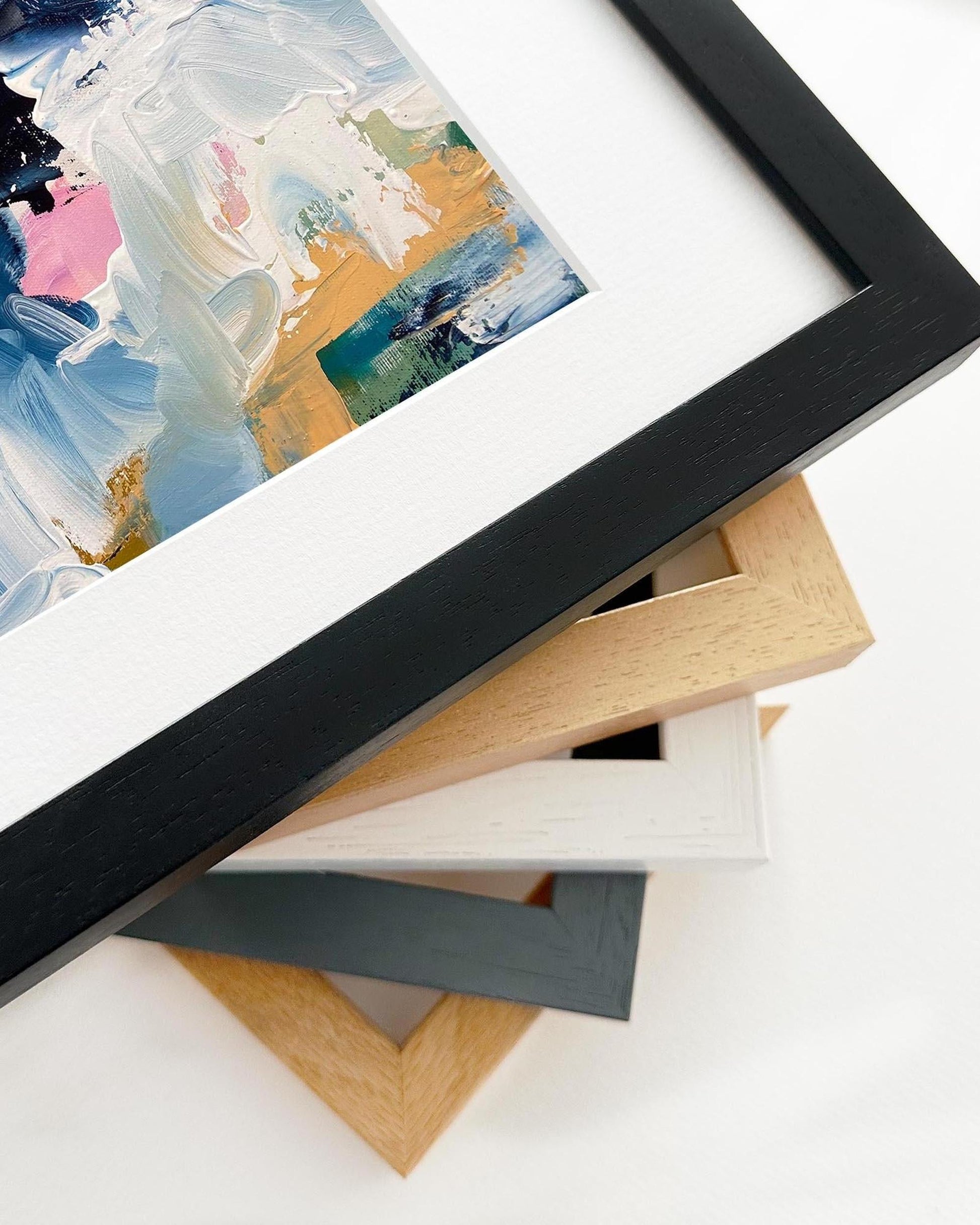 Stack of picture frames with a partially visible painting in the background