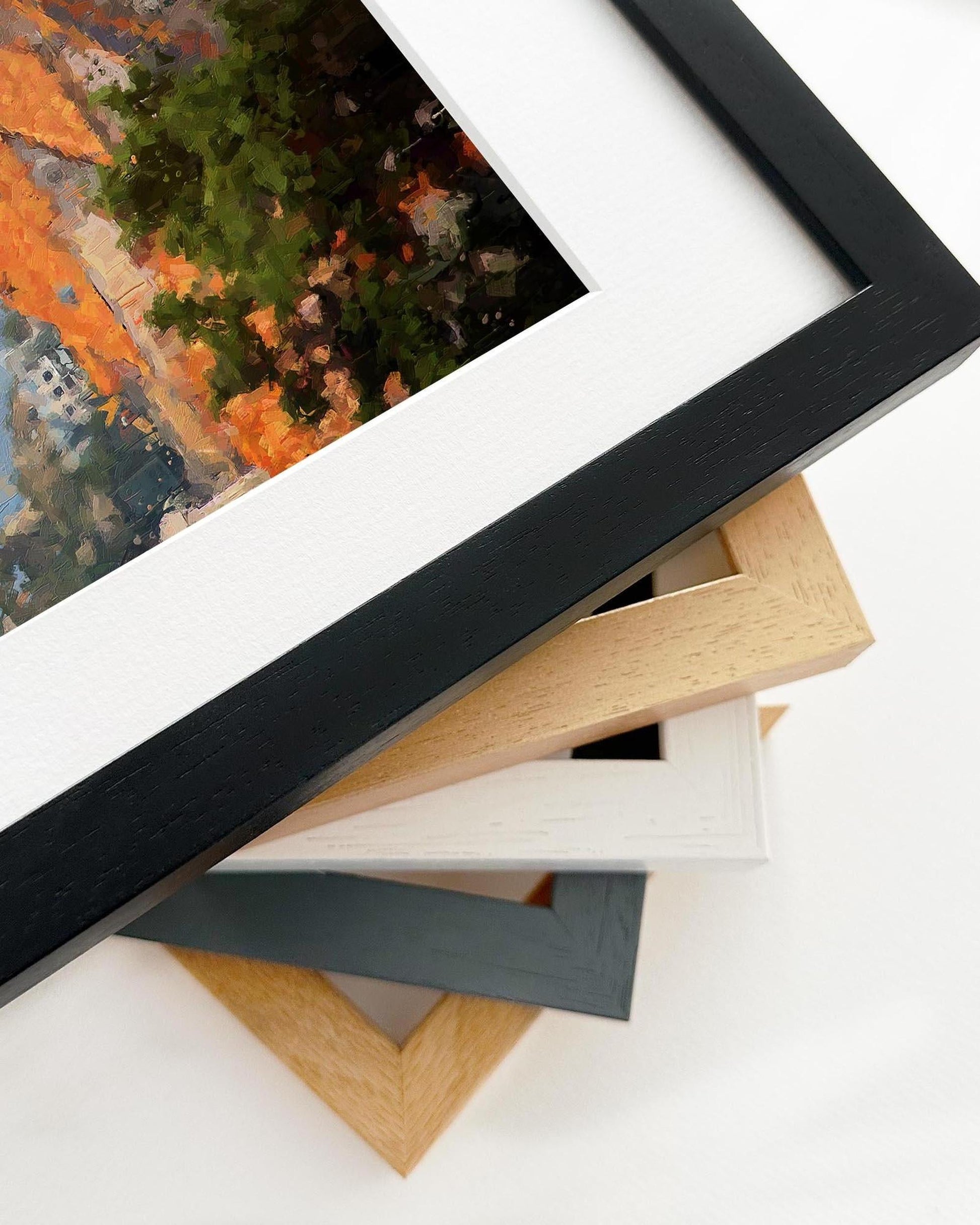 Collection of various picture frames on a white surface with a painting in the background.