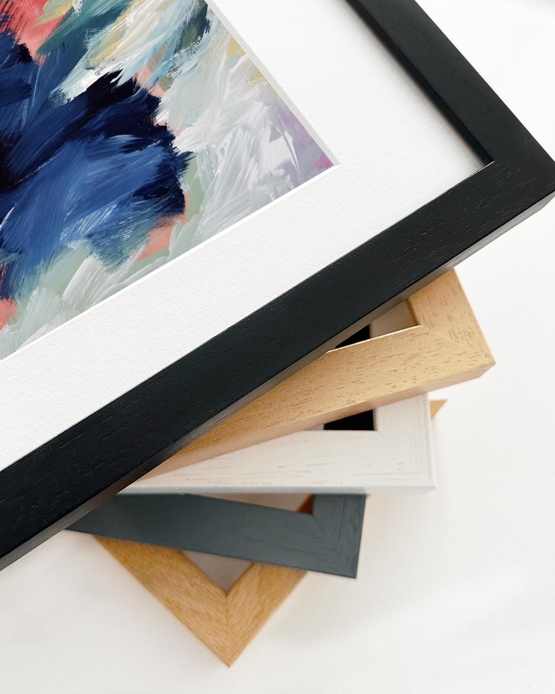 Close-up of various picture frames with a colorful painting in the background