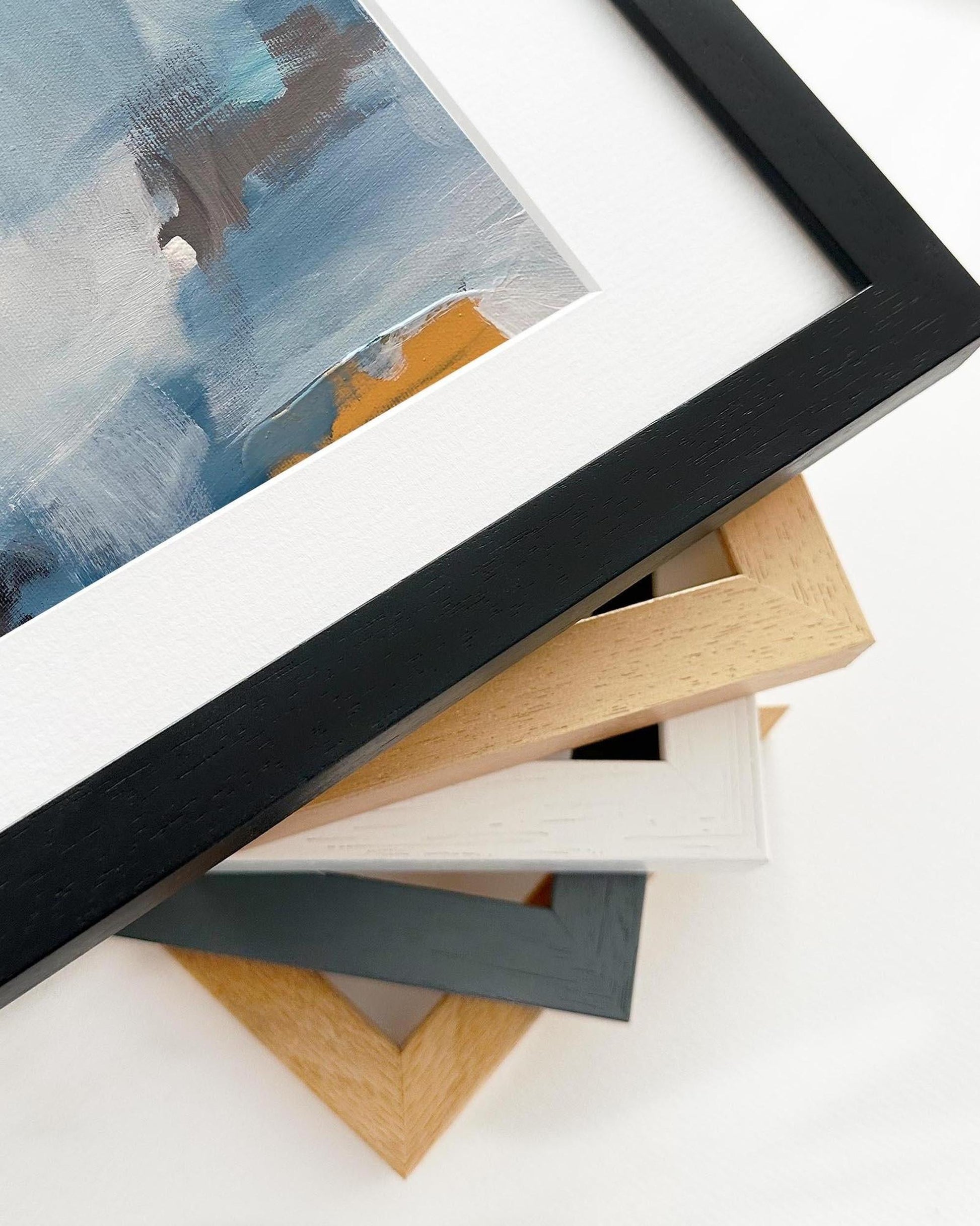Collection of various photo frames on a white surface with a partially visible painting.
