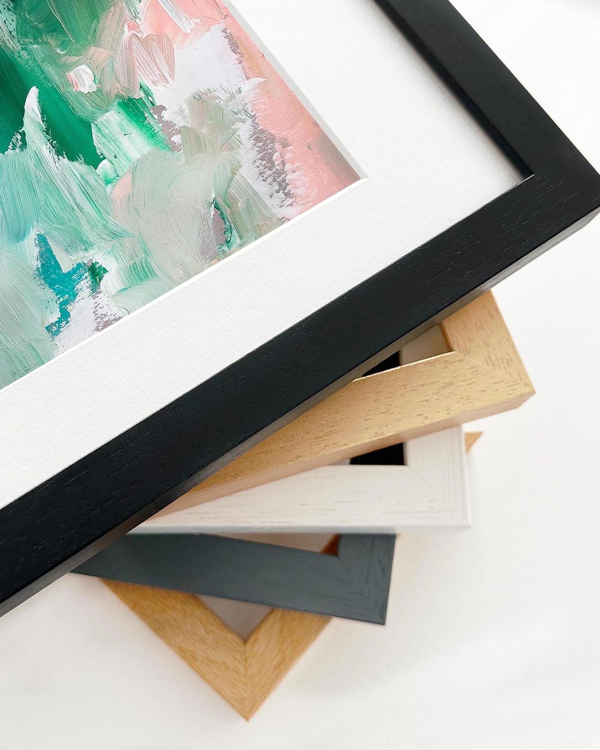 Close-up of various picture frames on a white surface with a partially visible artwork.
