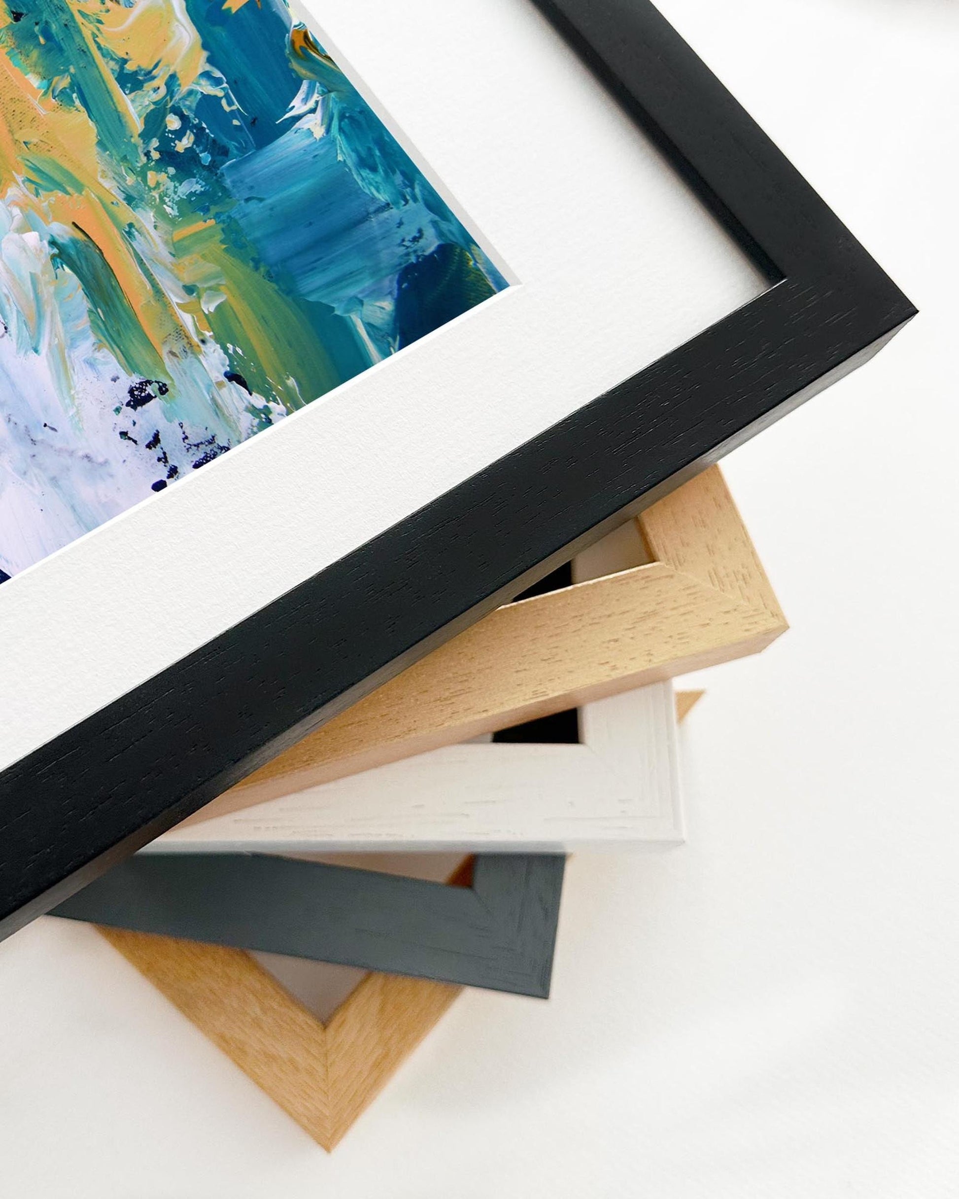 Close-up of various picture frames with a colorful abstract painting in the background.
