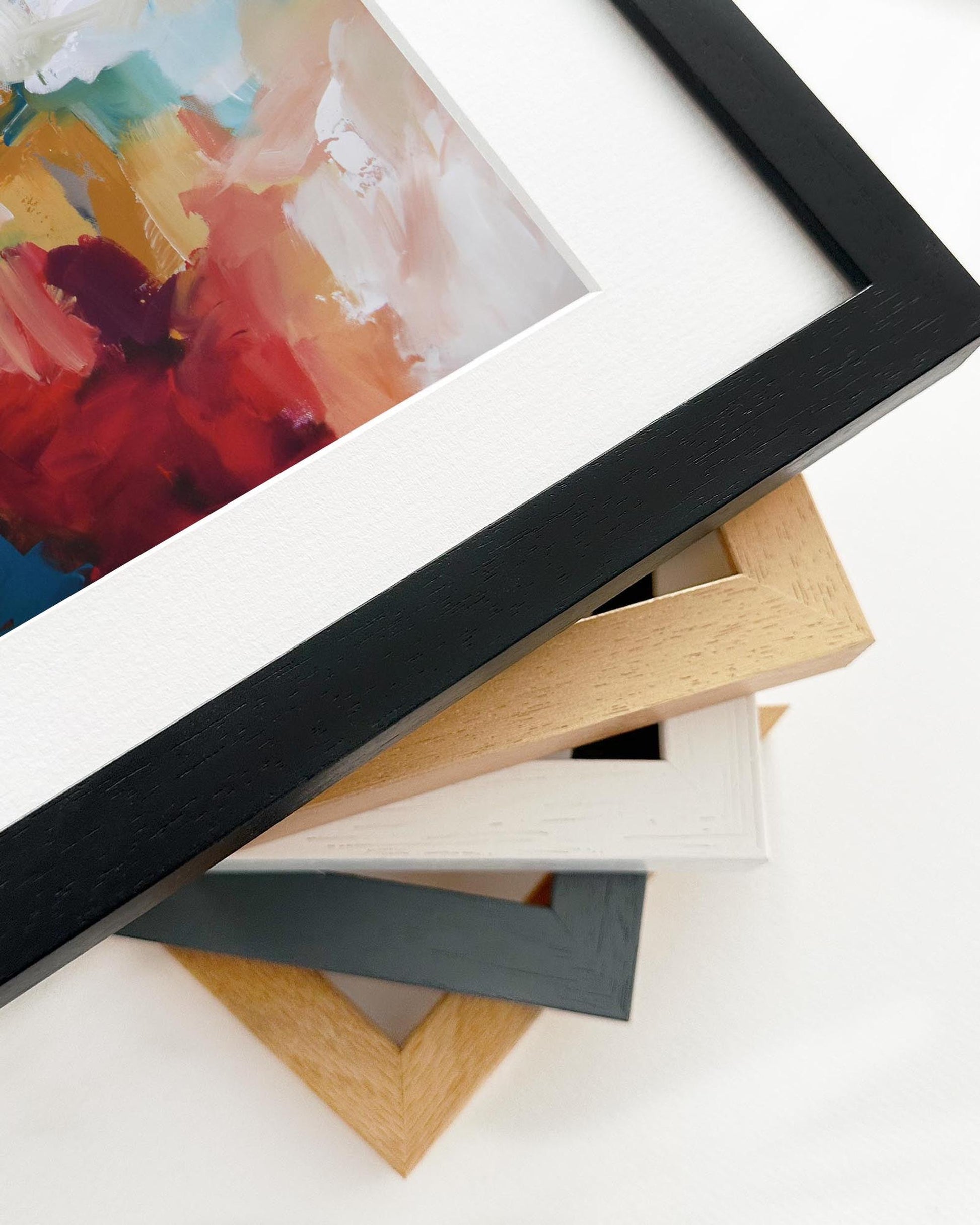 Stack of various picture frames with a framed painting on a white background