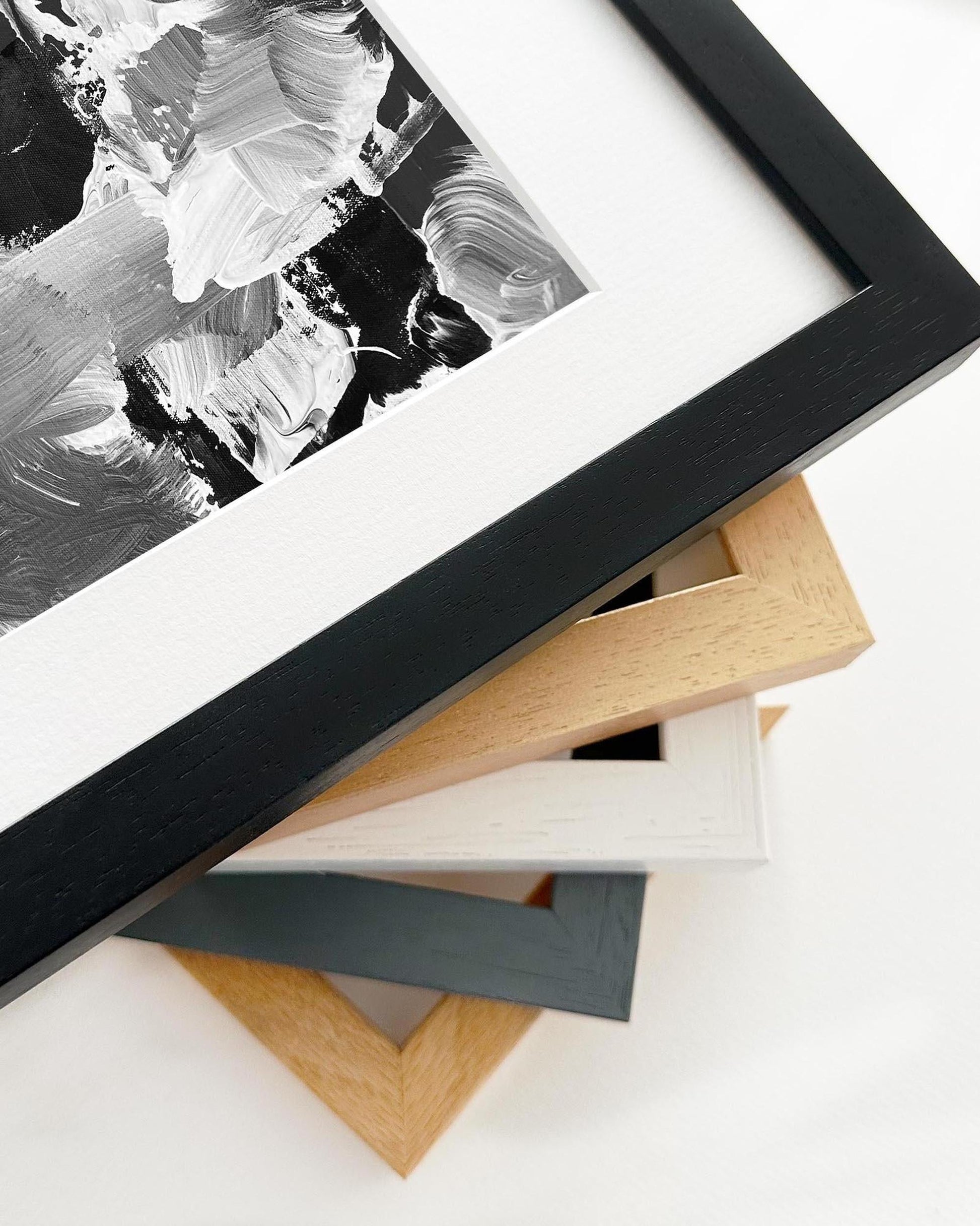 Close-up of various picture frames on a white surface with abstract art in the background.