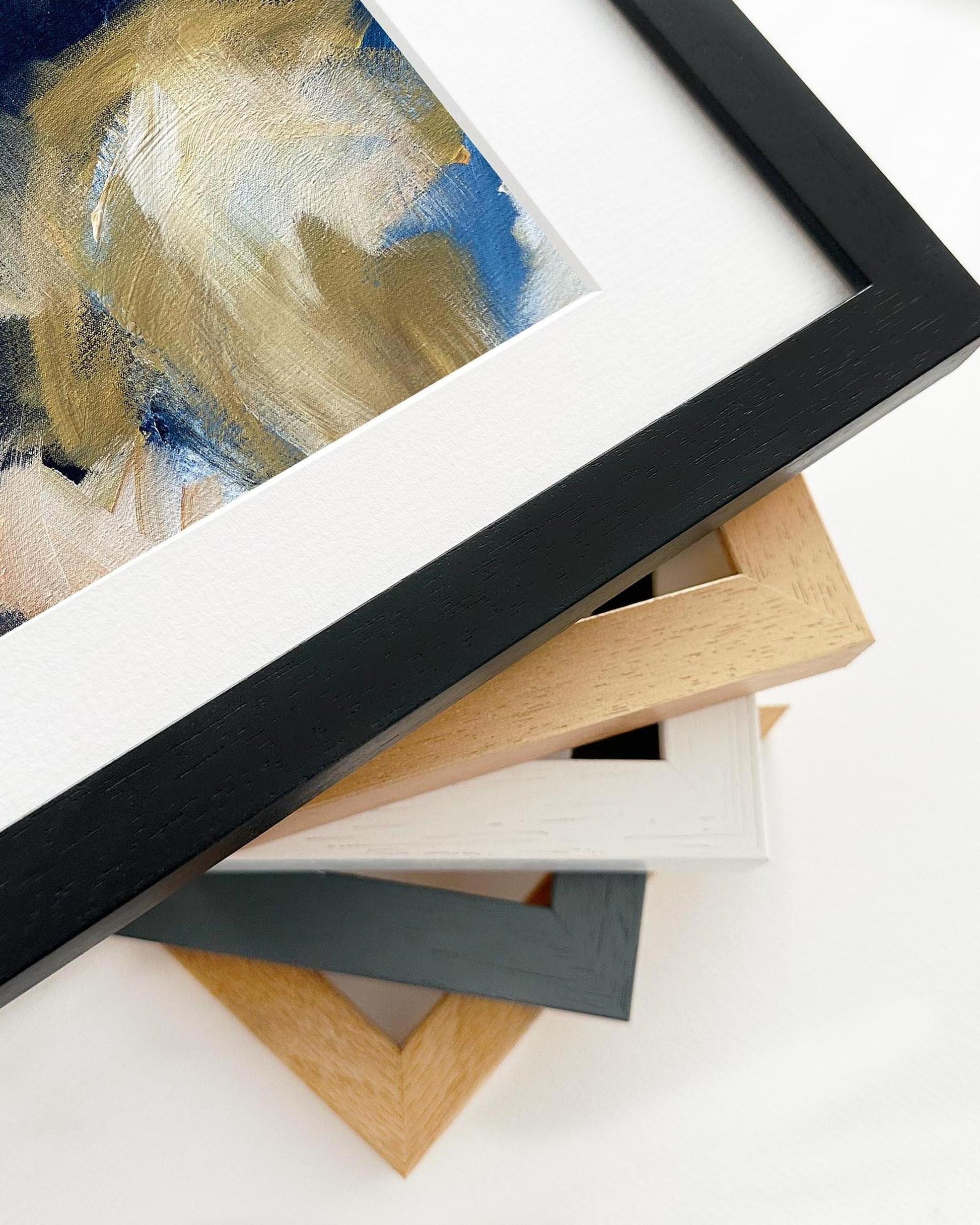 Collection of various picture frames on a white surface with abstract art in the background.