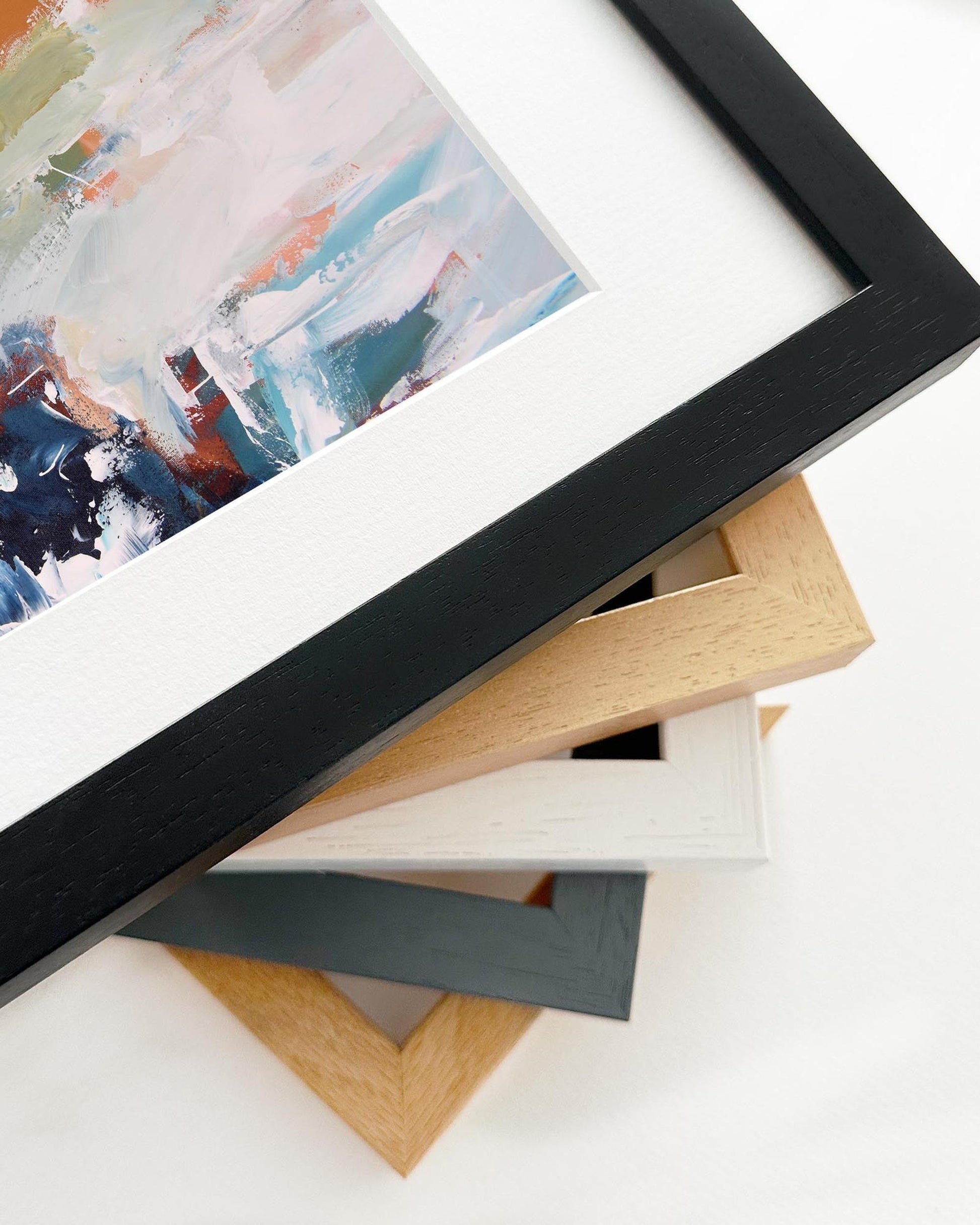 Close-up of various photo frames with a painting in the background