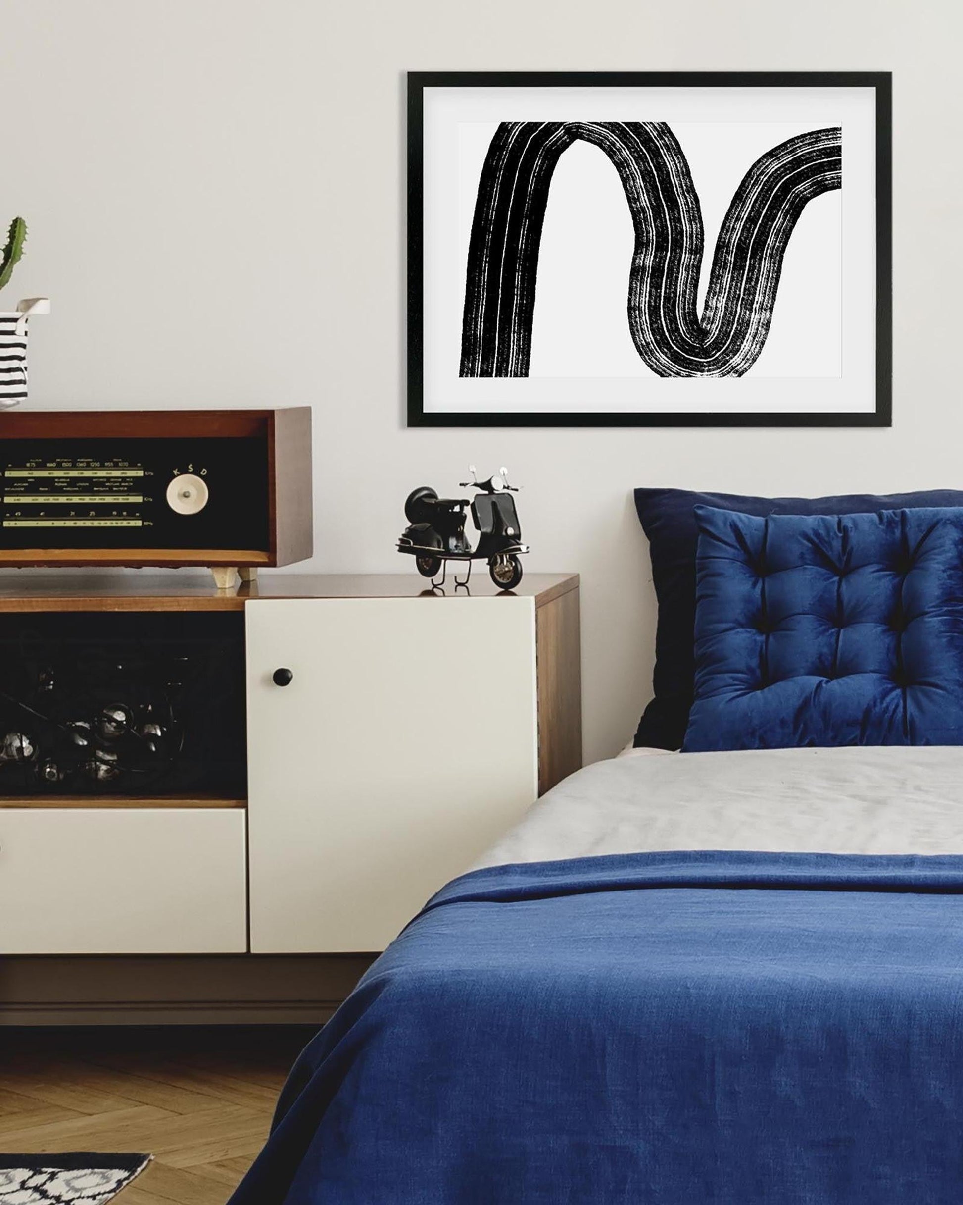 Modern bedroom with blue bedding, framed artwork, and vintage radio.