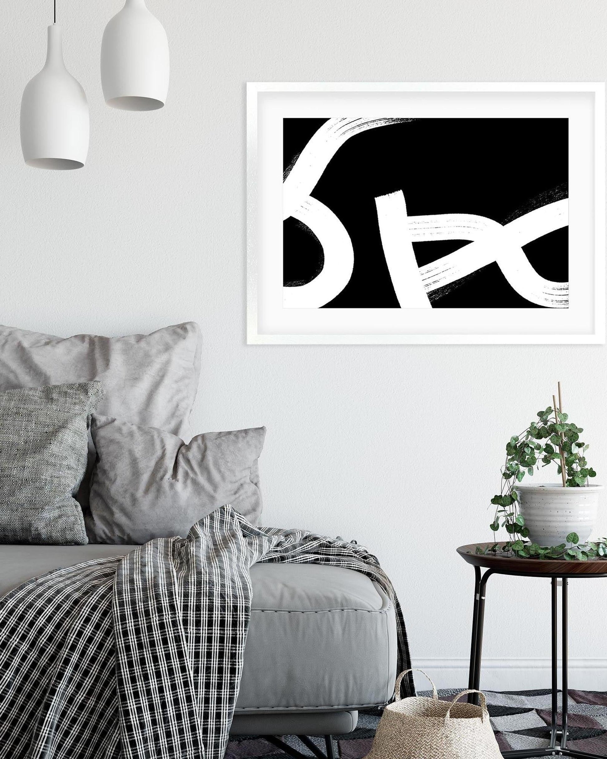 Living room with abstract black and white art on the wall, gray sofa, and small table with plant.